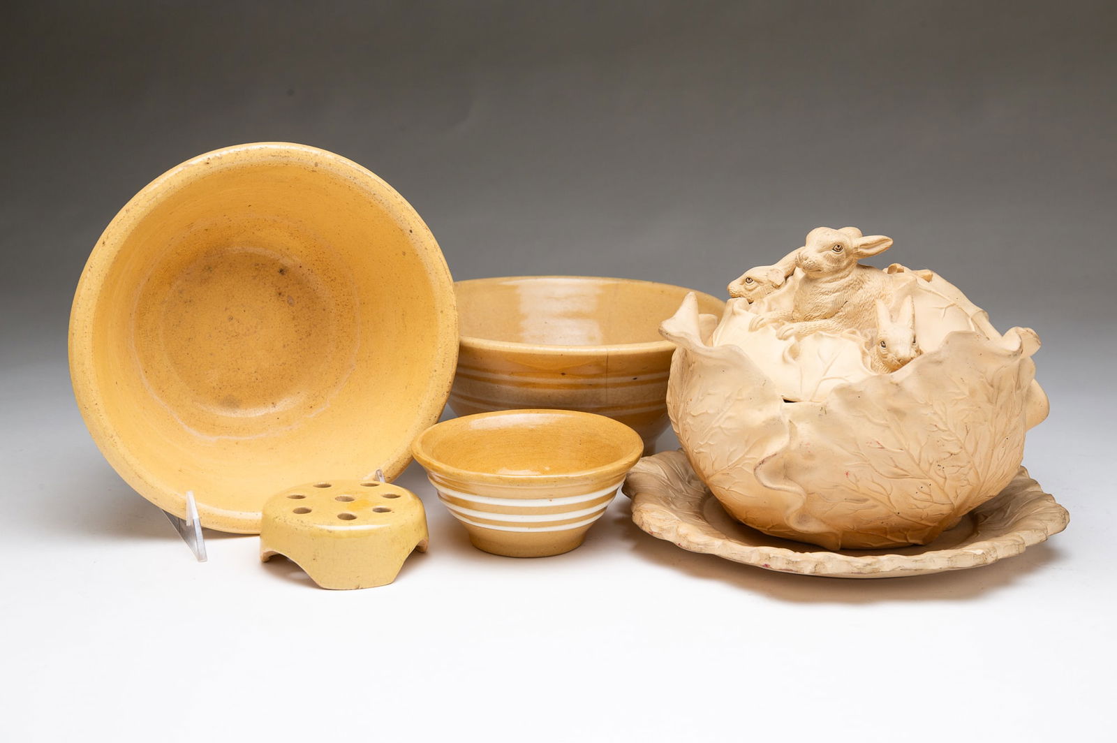 SIX YELLOWWARE ITEMS, INCL. FRENCH CABBAGE TUREEN WITH UNDERPLATE. Tureen, 6"h. 8.5"d.: 19th-20th Century. A French cabbage tureen and underplate with a rabbit family of four on the lid. Plus four American items including three Ohio bowls with white bands. 3.25" h. 7.25" dia. and one