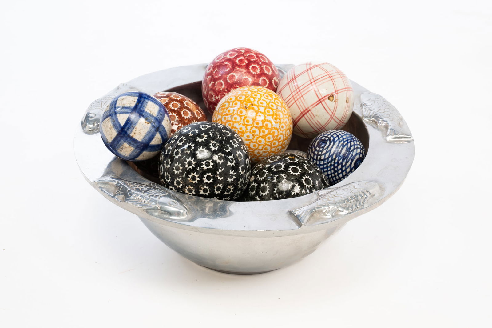 ELEVEN GLAZED CERAMIC CARPET BALLS IN A POLISHED ALUMINUM BOWL WITH FISH. Bowl, 5"h. 13"d.: English and other, ca. 1900 and later. A group of eleven ceramic carpet balls in various sizes and patterns presented within a contemporary polished aluminum bowl with a projecting rim decorated with