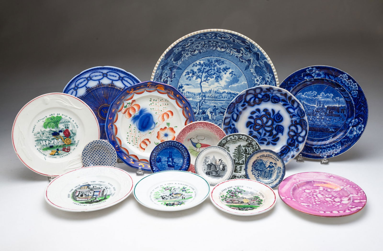 SIXTEEN STAFFORDSHIRE ITEMS, MOSTLY PLATES. Largest, 2.5"h. 12.25"d.: 19th Century. Enoch Wood "Fair Mount Near Philadelphia" bowl with stapled repair, Clews historical blue "Lafayette Landing At Castle Garden" plate, Martha Washington flow blue States plate, two flow b