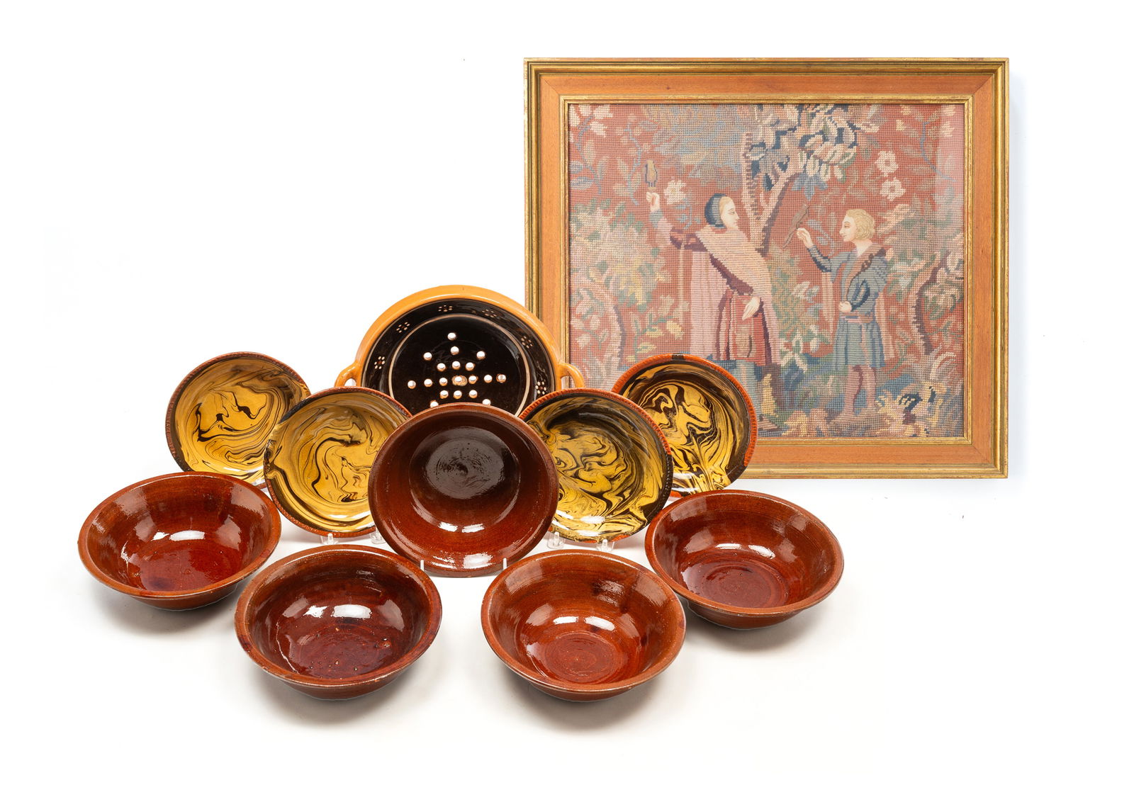 TEN AMERICAN REDWARE ITEMS, INCL. WILLIAMSBURG RESTORATION, AND AN AMERICAN NEEDLEPOINT PICTURE.: Redware, late 20th-early 21st century, comprising four Williamsburg Restoration shallow bowls with yellow and tan marbled high glaze, a handled colander with dark brown high glaze, white bands with st