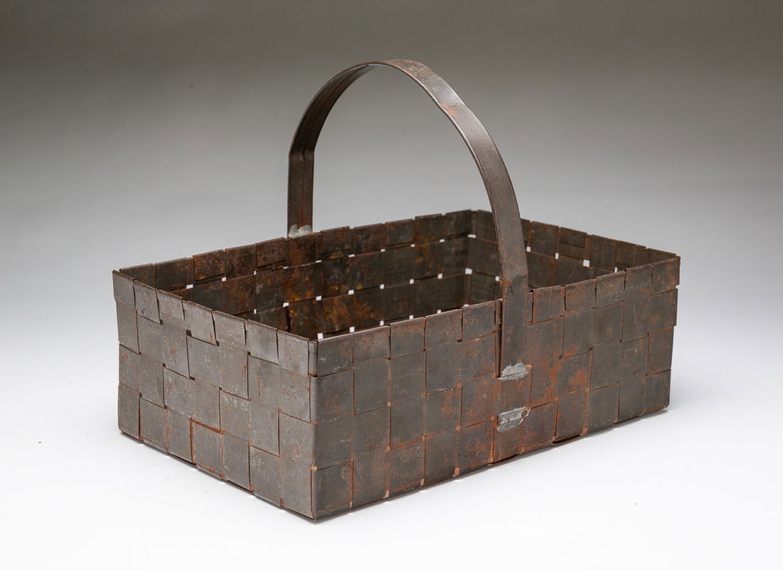 AMERICAN TIN ANNIVERSARY BASKET. 8.75"h. 11.5"w. 7.5"d.: Second half 19th Century. Nicely woven thin tin and high arched handle.SHIPPING: All purchases from Amelia Jeffers, Auctioneers & Appraisers may be picked up by you or your designated agent / shipper