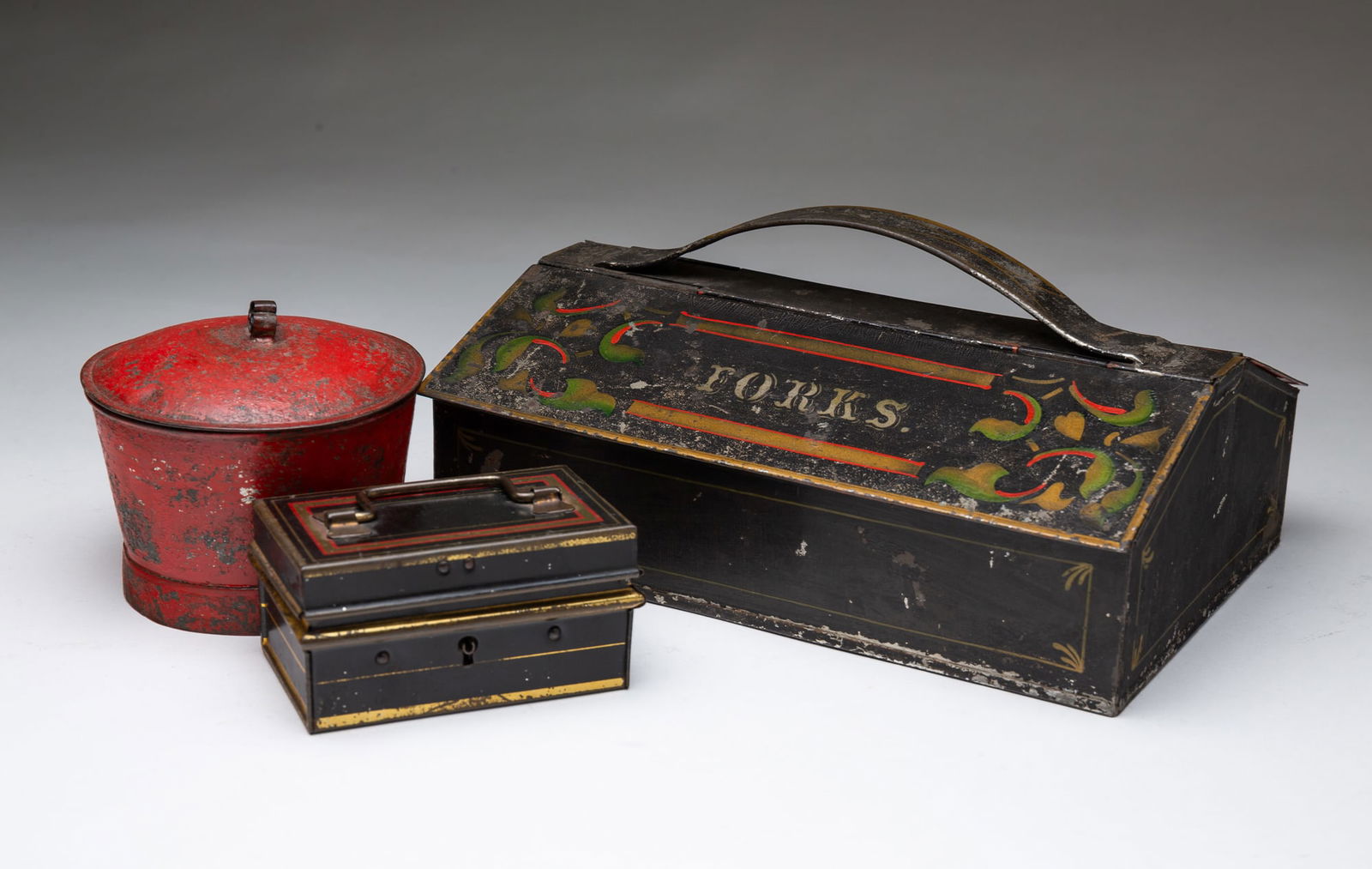 THREE TOLEWARE ITEMS, INCL. CUTLERY BOX. Sugar, 3.25"h. 4.25"d.: Second half 19th Century. American red lidded sugar. American cutlery box with hinged lids, green, red, and gold carriage striping and flourishes. In silver on lids "Spoons" and "forks". And an Englis