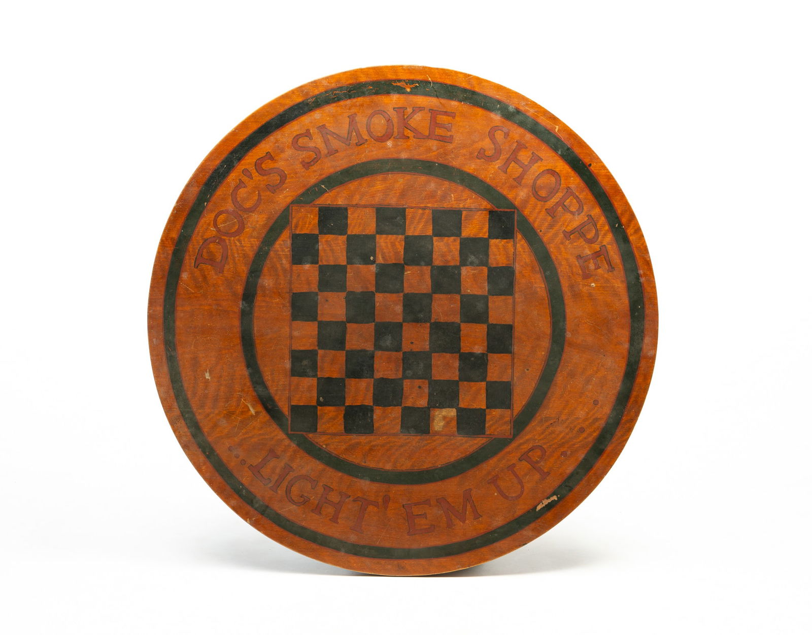 AMERICAN PAINTED GAMEBOARD TABLETOP. 36"d.: Lebanon, Ohio, Early 20th Century. Circular tabletop with battens, top painted in the round "DOC'S SMOKE SHOPPE LIGHT "EM UP" with a checkerboard to center.SHIPPING: All purchases from Amelia Jeffers,