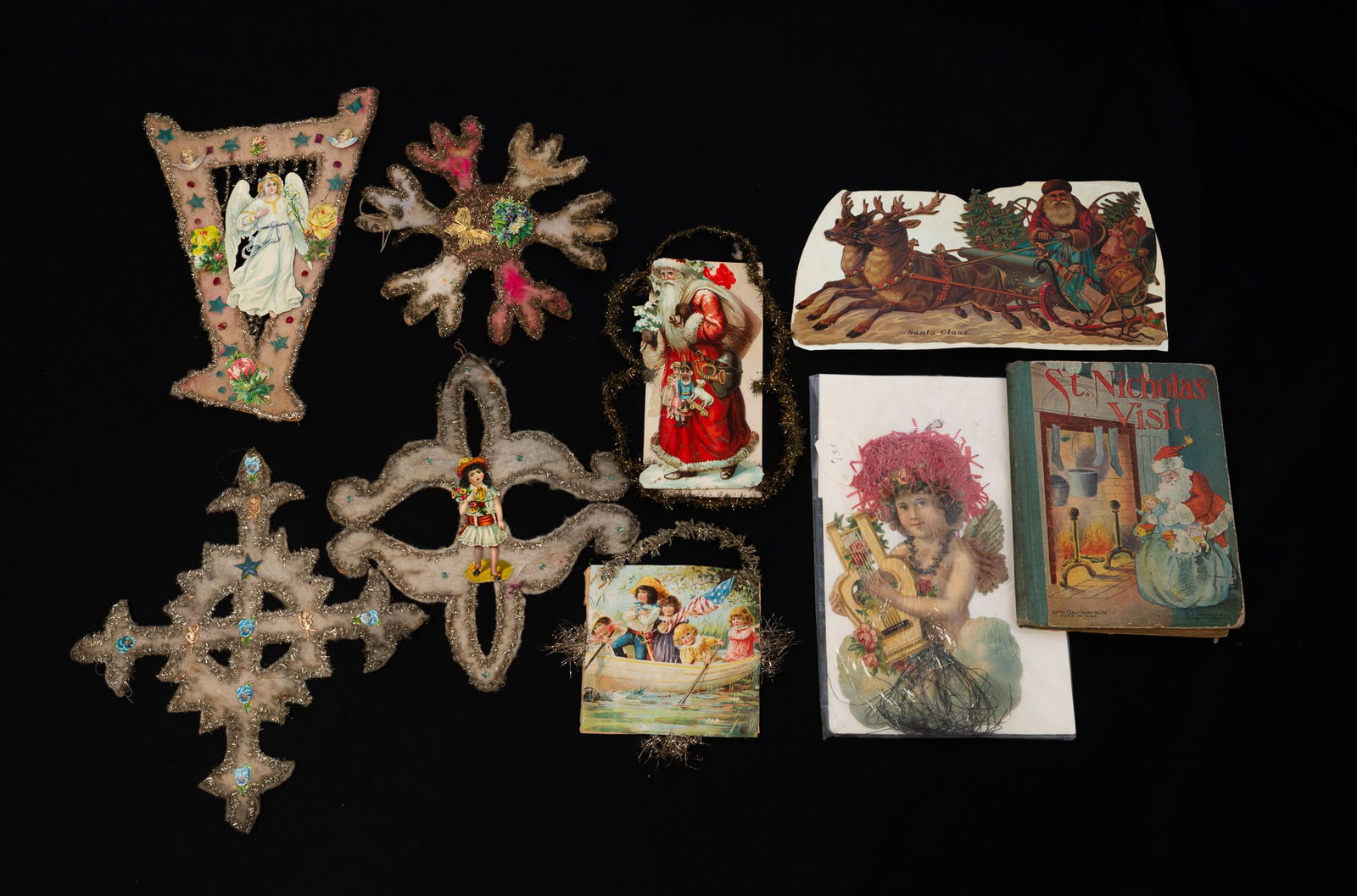 COLLECTION OF VICTORIAN PAPER, TINSEL, AND COTTON CHRISTMAS ORNAMENTS WITH M.A. DONAHUE & CO. "ST.: American, Early 20th Century. Comprising large paper and tinsel decorations, some embellished with cotton; together with a paper Santa Claus on his sleigh, an angel playing a lyre, and a "St. Nicholas