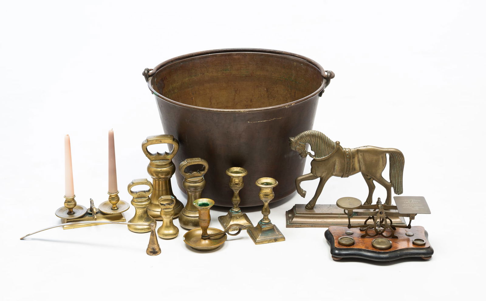COLLECTION OF ENGLISH AND AMERICAN BRASS ITEMS, INCL. IRON-HANDLED KETTLE. Kettle, 11"h. 15.5"d.: 19th Century. A H.W. Hayden's Patent spun brass kettle with iron bale handle, four brass weights, horse doorstop, pair of candle sticks with wave bases, a chamberstick, double chamber stick on a recta