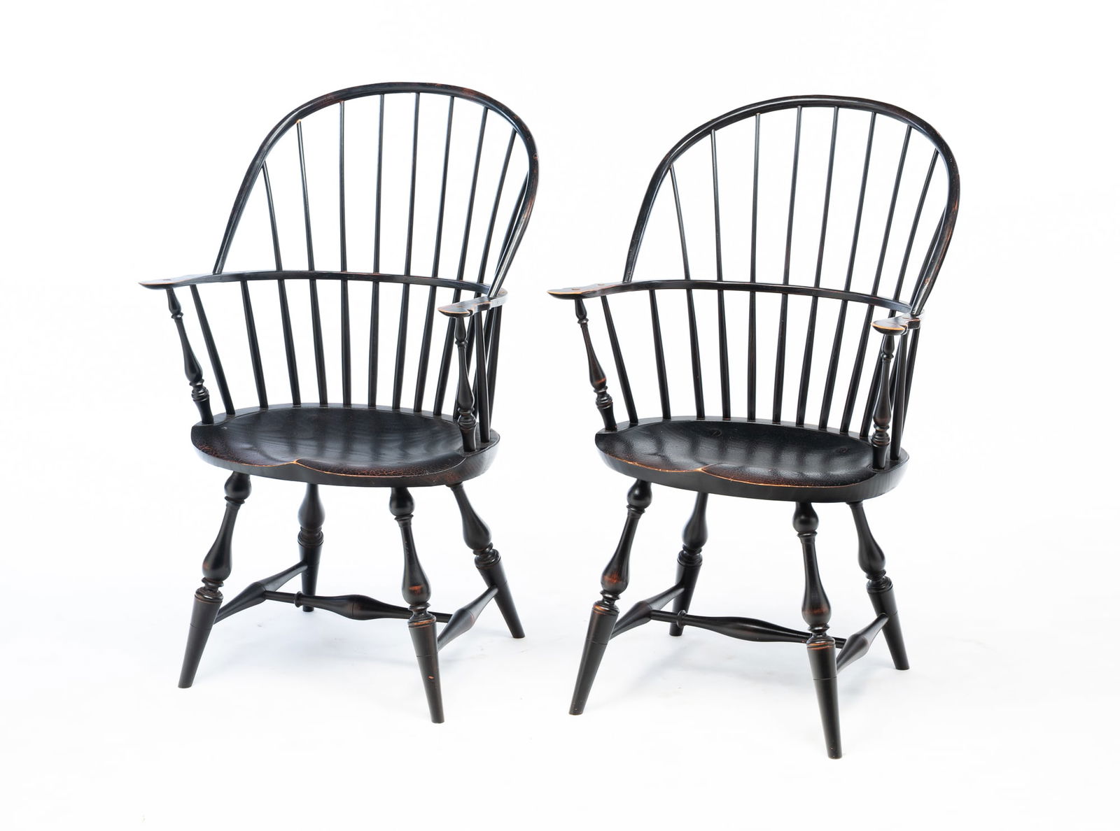 PAIR OF RIVER BEND CHAIR CO. (LEBANON, OHIO) EBONIZED SACK-BACK WINDSOR ARMCHAIRS. 38.5"h. 17.5": American, Late 20th Century. Spindle backs, shaped arms, oval seats, nicely turned stiles, legs, and stretchers. Distressed black paint and incised label under seats.Provenance: The Lifetime Collectio