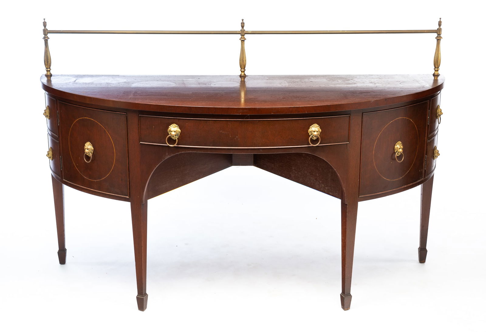 KITTINGER HEPPLEWHITE STYLE BRASS-MOUNTED MAHOGANY DEMILUNE SIDEBOARD. 46.5"h. 42"w. 26"d.: American, Mid-20th Century. Brass rail across back with balusters having urn finals, demilune shape, center drawer flanked by two hinged doors and double false drawer fronts on ends, lion's head ring