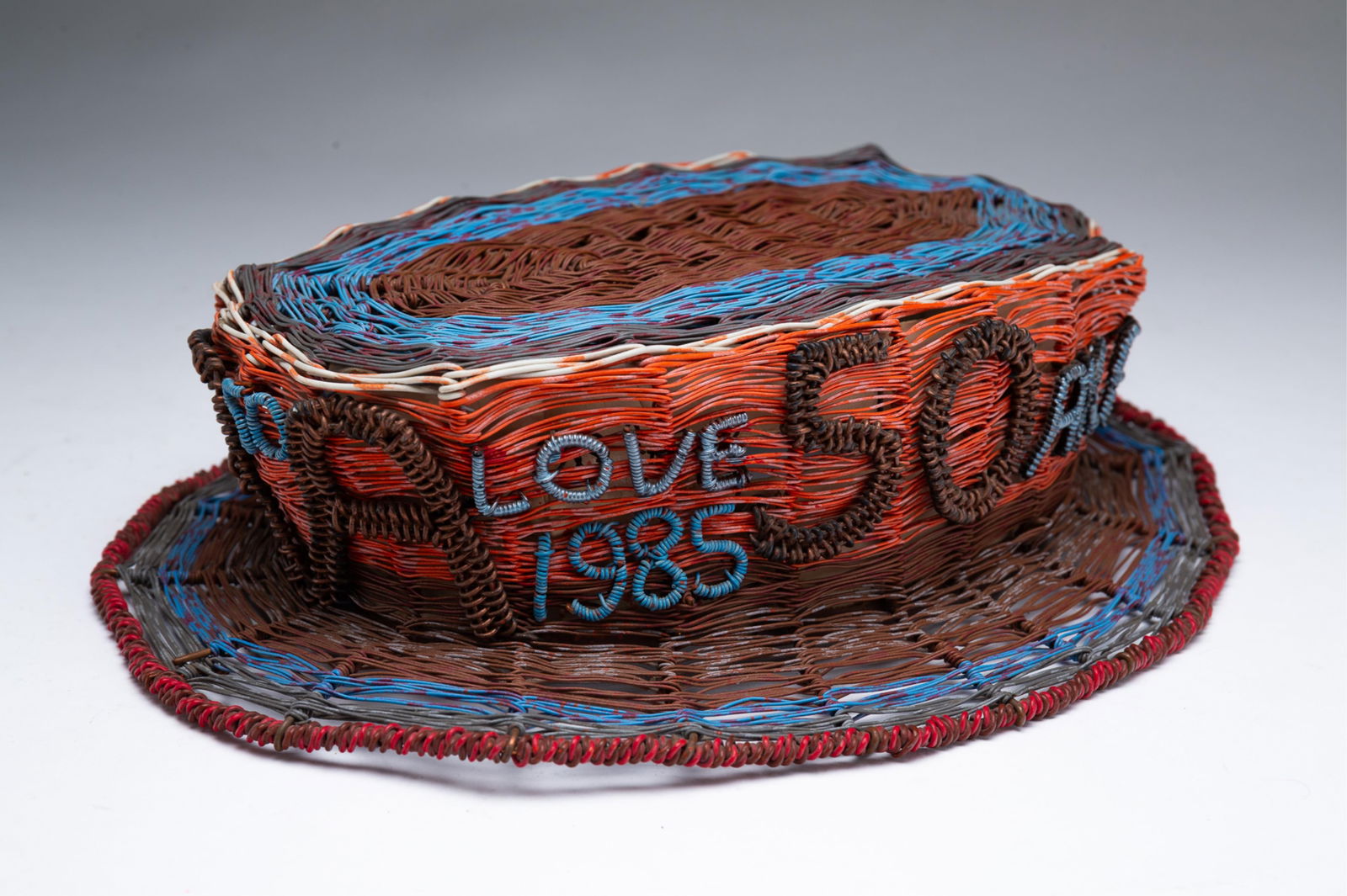 W.D. "CRAZY MAC" MCCAFFREY (AKRON, OHIO, 1923 - 1993) "AA CELEBRATION HAT" OUTSIDER ART COLORED WIRE: American, 20th Century. A top hat in red, white, and blue, celebrating the 50th anniversary of the founding of Alcoholics Anonymous. Hat decorated with Akron, Ohio, 50, Love, 1935, and 1985 around