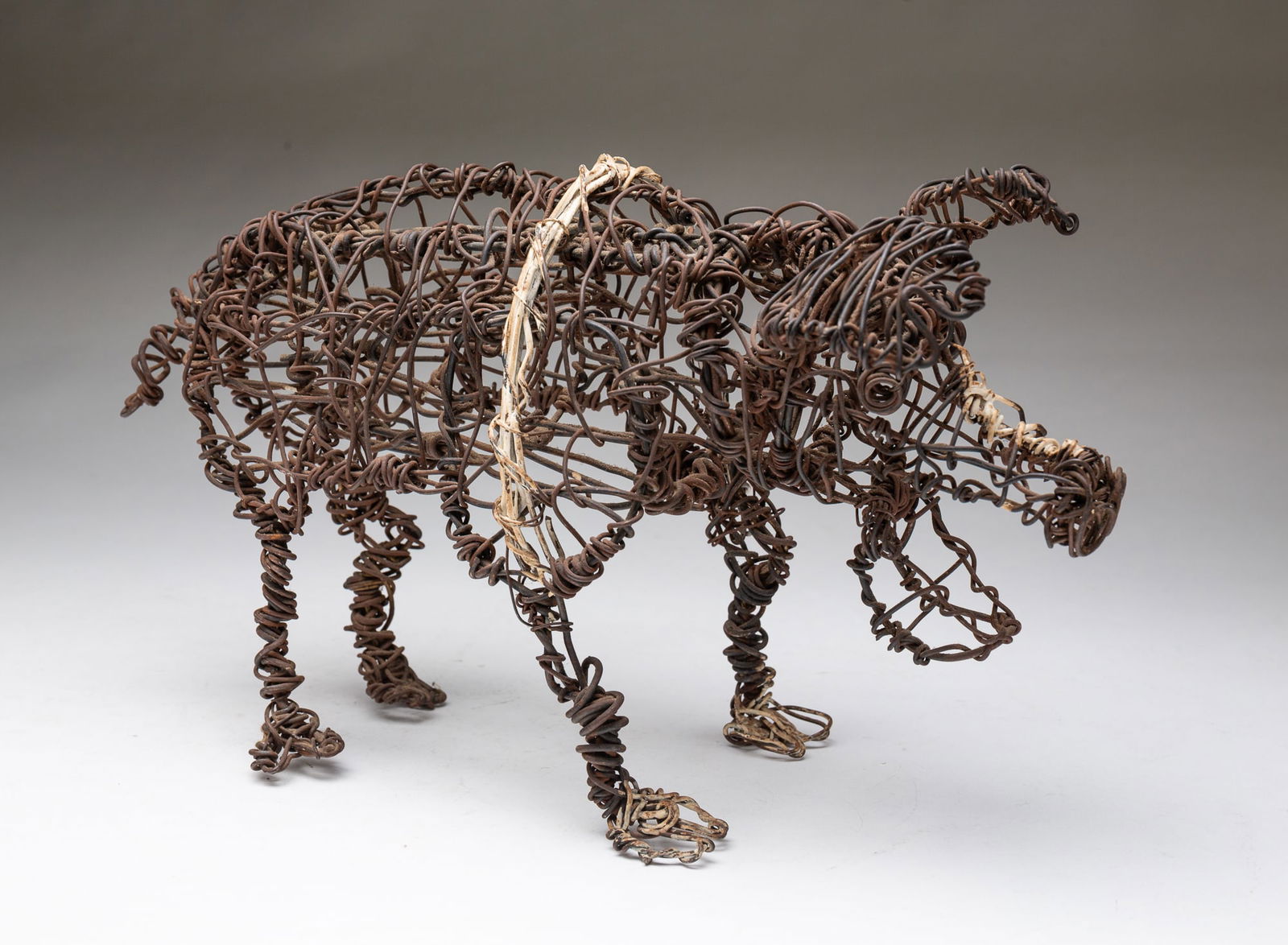 BRUTALIST TWISTED WIRED PIG SCULPTURE. 7.5"h. 5.5"w. 15"d.: American, 20th Century. Twisted wire with a hinged mouth, a painted white stripe, and painted feet.Provenance: From the Lifetime Collection of Chuck Auerbach.SHIPPING: All purchases from Amelia Jeffer