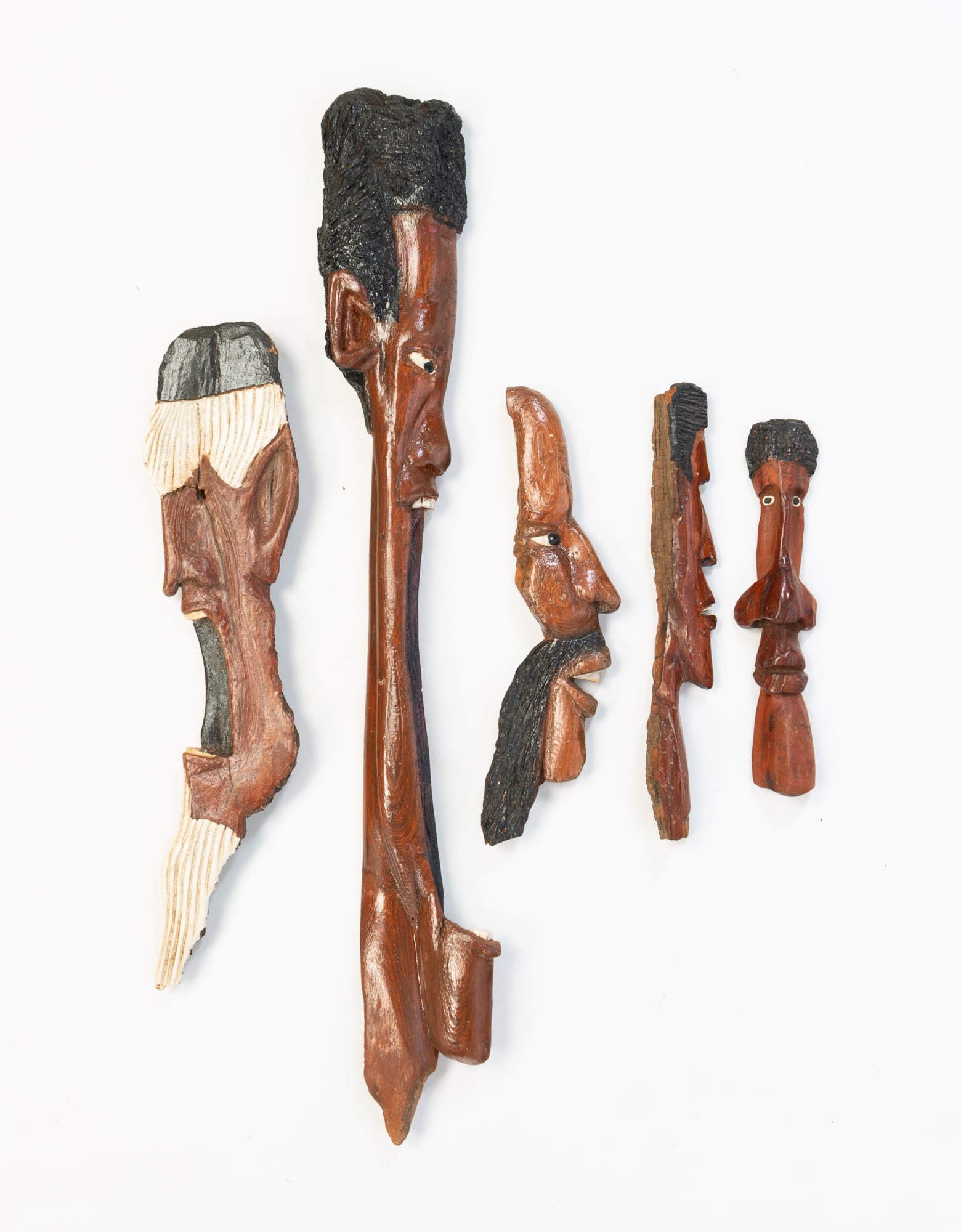 FIVE RON COLLINS (AKRON, OHIO) BLACK AMERICANA BARK CARVINGS. Largest, 21"h. 3"w.: American, 20th Century. All profiles of men's heads in various poses. Two signed "R.C." and three with wire stands.Provenance: From the Lifetime Collection of Chuck Auerbach.SHIPPING: All purchases fr