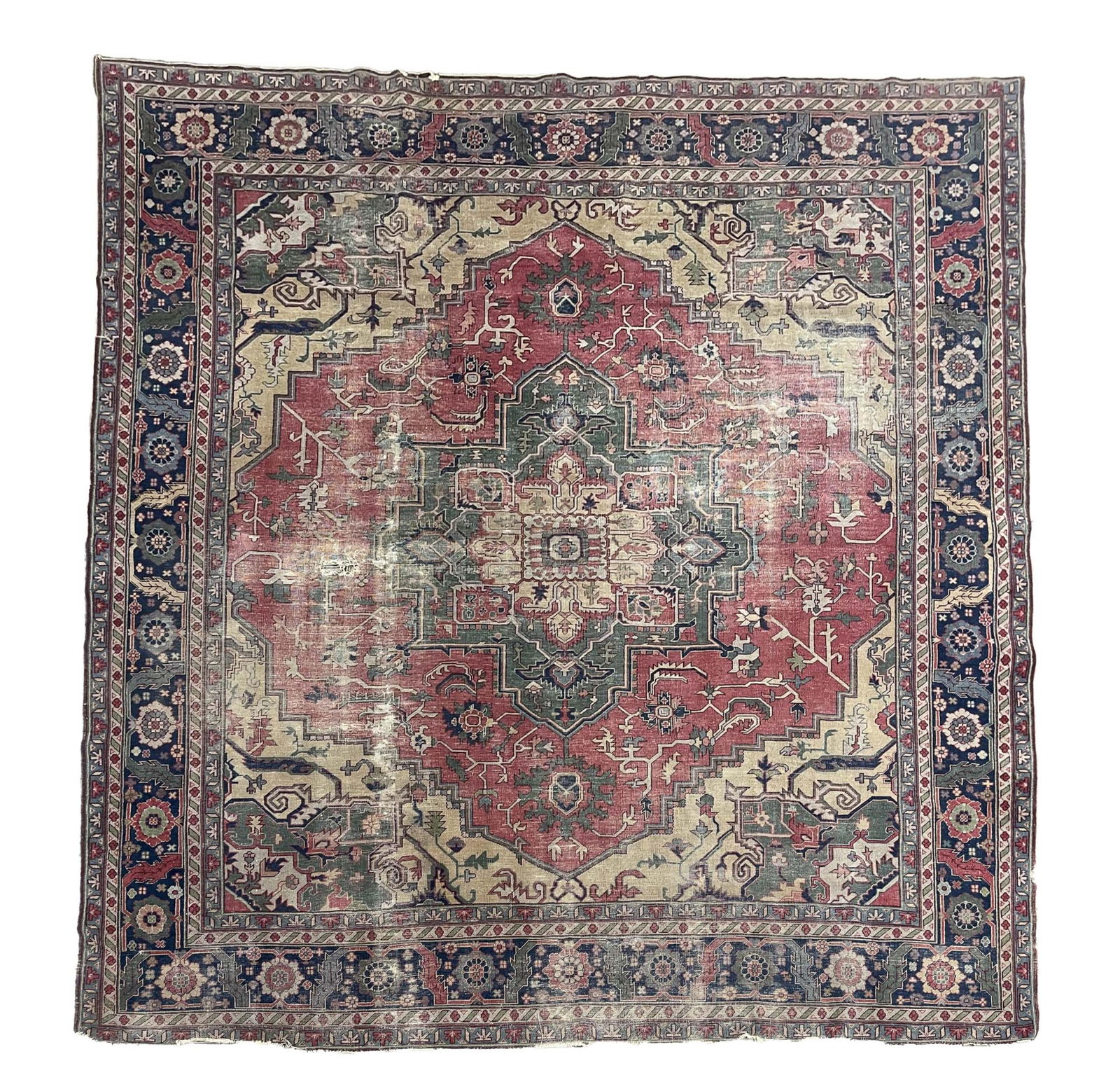 PERSIAN HERIZ WOOL ROOM-SIZE RUG WITH RARE GREEN COLOR. 135"w. 146"l.: Iran, Early 20th Century. Hand-knotted. Having an all-over angular, stylized floral, foliate, and vine pattern, within a central green and cream medallion on red ground, with tan and green spandrels a