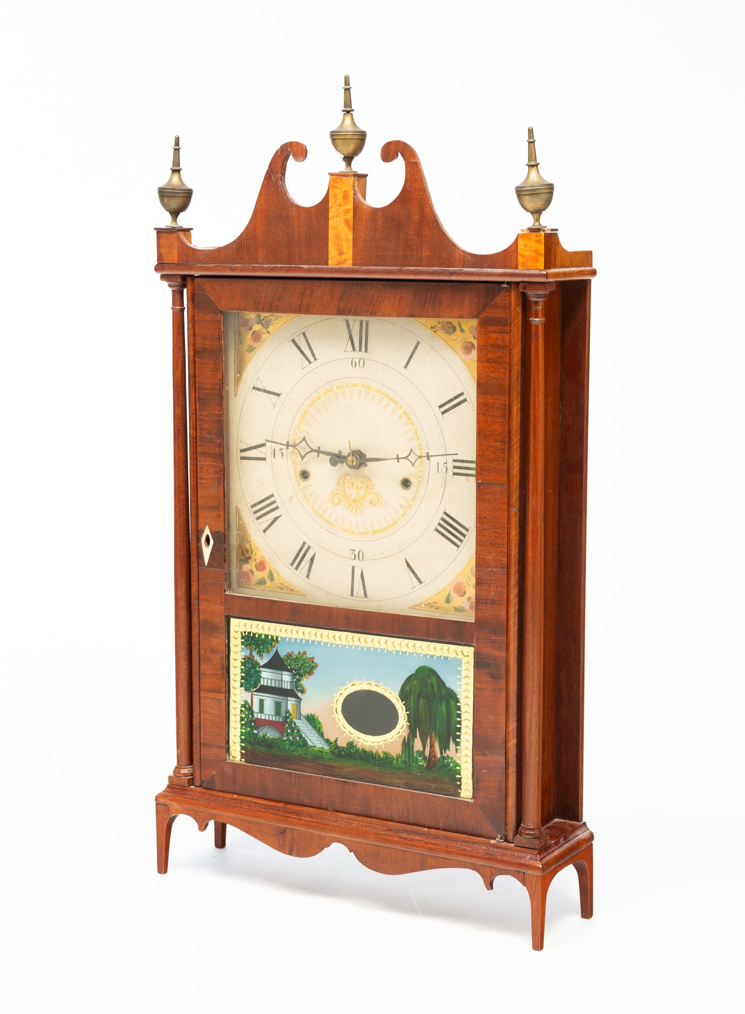 SETH THOMAS MAHOGANY PILLAR AND SCROLL MANTEL CLOCK.: American, First half 19th Century. Mahogany veneer and pine case. Broken arch pediment with brass urn finials, slender full pilasters, high cut-out legs, shaped apron, lower reverse-painted scenic tab