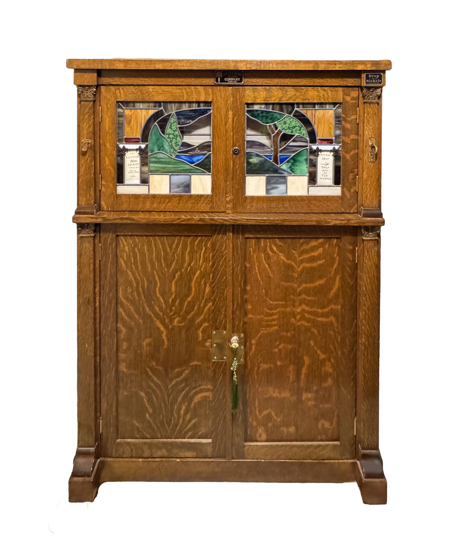 J.P. SEEBURG COIN-OPERATED MUSIC CABINET.: American (Chicago, Illinois), Early 20th Century. Quarter-sawn oak coin-operated music cabinet, marked J.P. Seeburg Piano Company, Chicago, with stained-glass upper doors and paneled lower doors. 51.5
