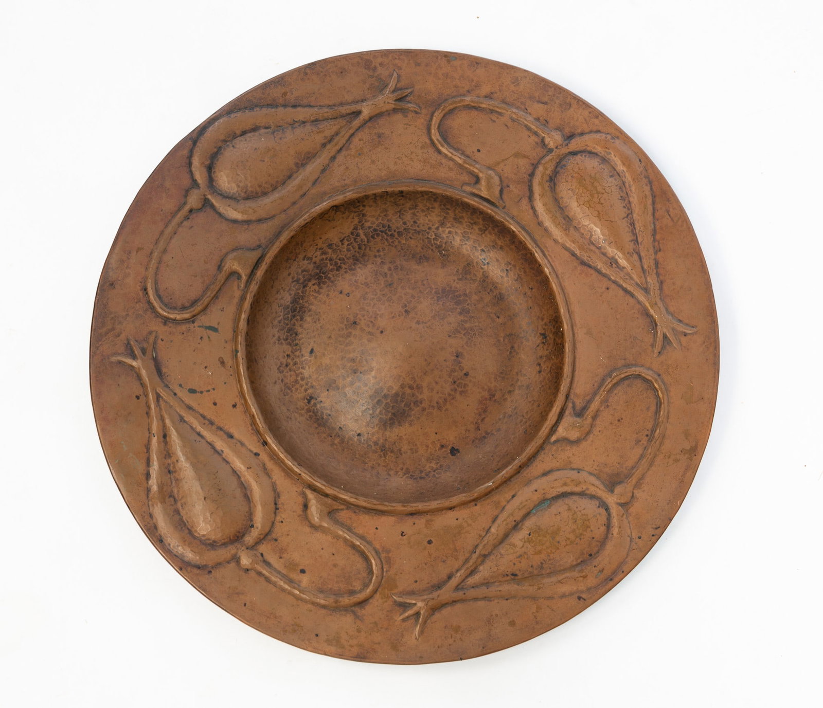 GUSTAVE STICKLEY (AMERICAN, 1858-1942) ARTS AND CRAFTS HAMMERED COPPER "SEED POD" CHARGER.: Ca. 1910. Large round charger with shallow bowl and large rim decorated with seed pods, marked with round "Gustave Stickley The Craftsman Workshop" stamp on underside. 1.25"h. 20"dia.Provenance: From