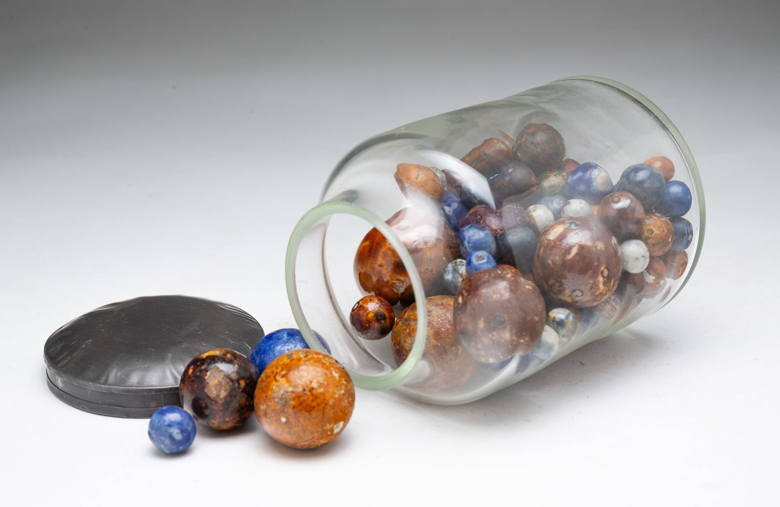 GLASS JAR FILLED WITH CLAY MARBLES.: 19th Century. Mostly glazed marbles in varying sizes. In a new glass jar with a mismatched tin lid. 6"h. 3.75"d.