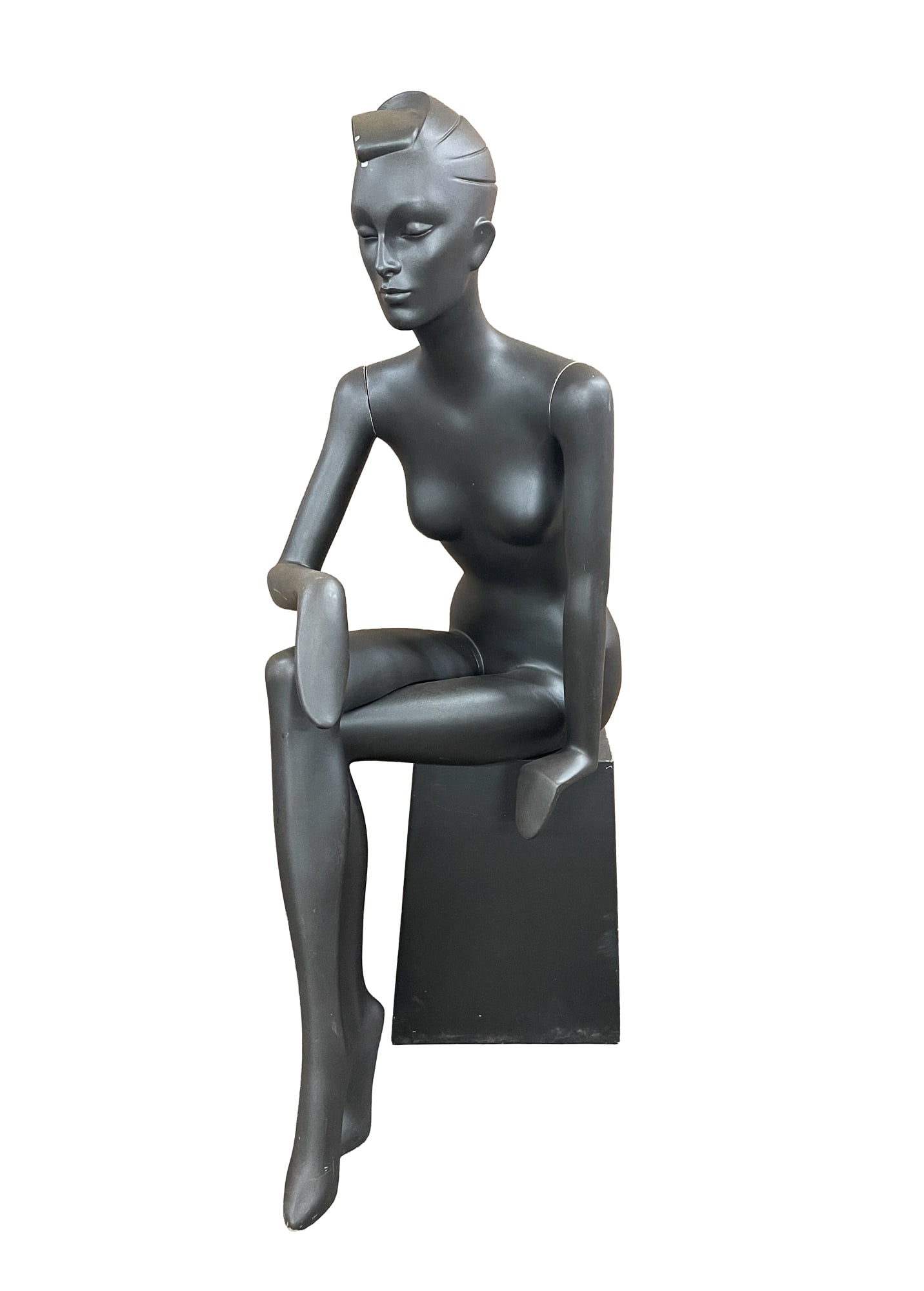 FIBERGLASS SEATED FEMALE MANNEQUIN FIGURE.: American, Late 20th Century. Dark-gray painted 1980s-style female form seated with legs crossed on a canted base. 55"h. 15"w. 30"d.Provenance: From the late George Shahady (Bridgeport, West Virginia).