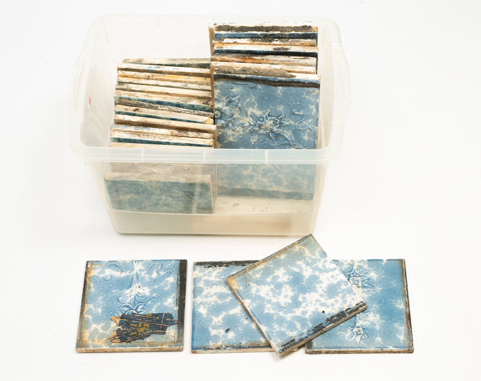 TWENTY-FOUR AMERICAN FIREPLACE SURROUND TILES.: TWENTY-FOUR AMERICAN FIREPLACE SURROUND TILES. Late 19th Century. Floral Adamsesque embossed pattern in a light blue mottled glaze. Seven, 9"h. 6"w. and seventeen, 6"h. 6"w. Provenance: From the late
