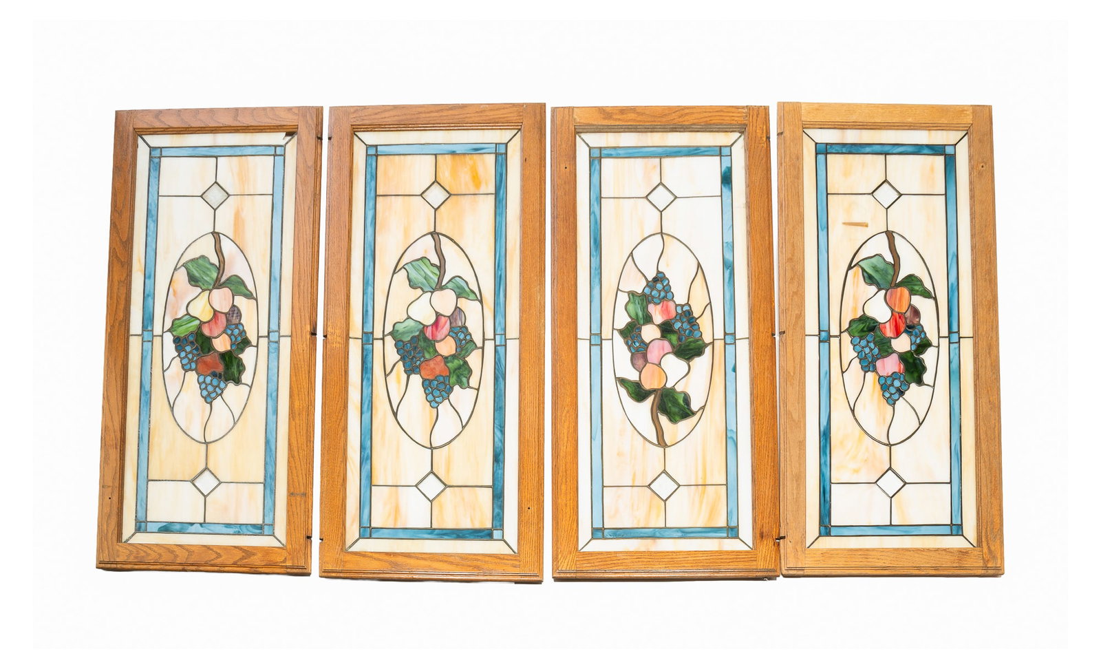 FOUR AMERICAN STAINED AND LEADED GLASS WINDOWS.: FOUR AMERICAN STAINED AND LEADED GLASS WINDOWS. Late 20th Century. Carmel slag with blue slag border, oval reserve with bunches of fruit, and diamond-shaped beveled clear glass medallions. In oak fram