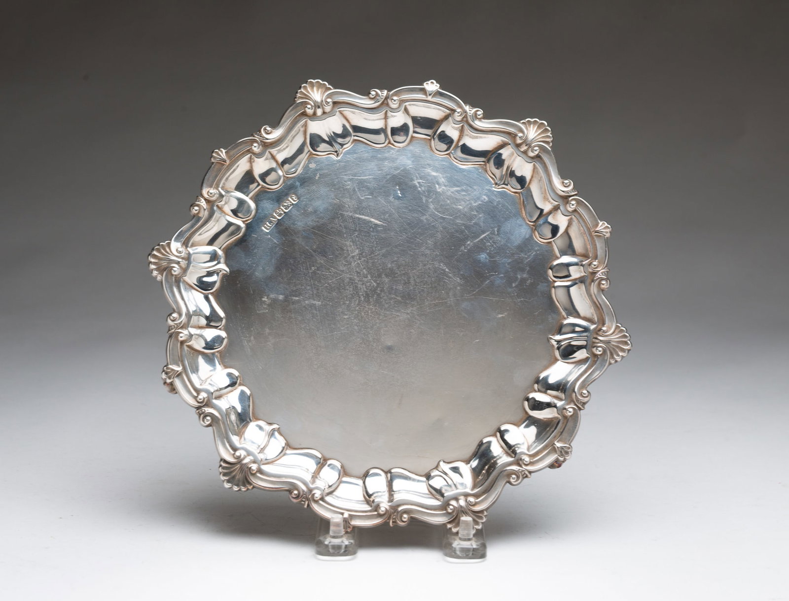 LONDON STERLING SILVER SALVER.: English, 1899. Footed, shaped-edge salver with foliate and shell decoration. 1"h. 8.75"d. Approximately 10.8 ozt.**Note: Bidders who are not yet established with our firm will be required to pay for