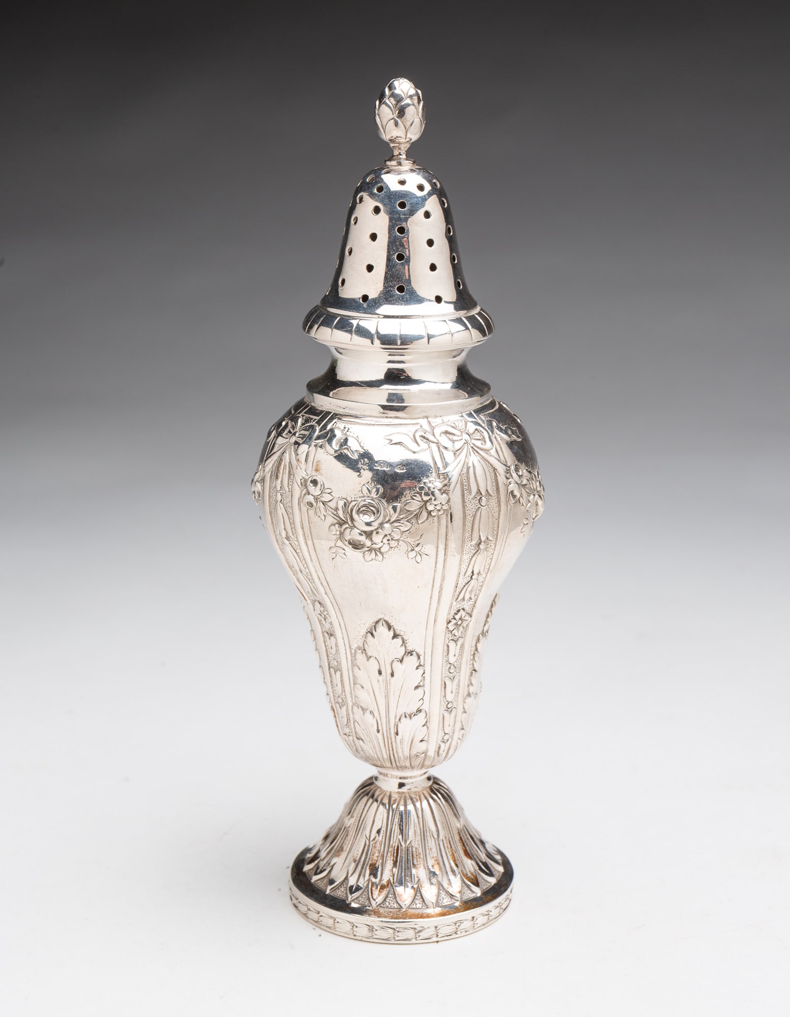 EUROPEAN SILVER MUFFINEER.: Ca. 1900. Well cast floral and foliate decoration, perforated domed lid with pinecone finial, and nicely shaped body on raised foot. Indistinct hallmarks. 8"h. Approximately 6.6 ozt.**Note: Bidders