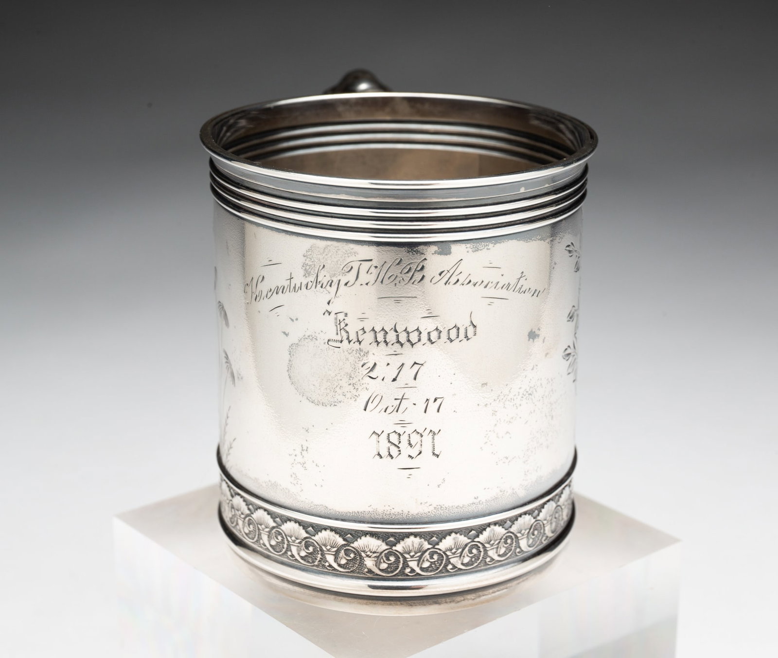 GORHAM STERLING SILVER TROPHY MUG.: American, ca. 1900. Cylindrical mug with shaped handle, cornucopia border to bottom, banded borders to top, engraved with floral decoration and engraved details of "Redwood" on Oct. 17 1891". 3"h.