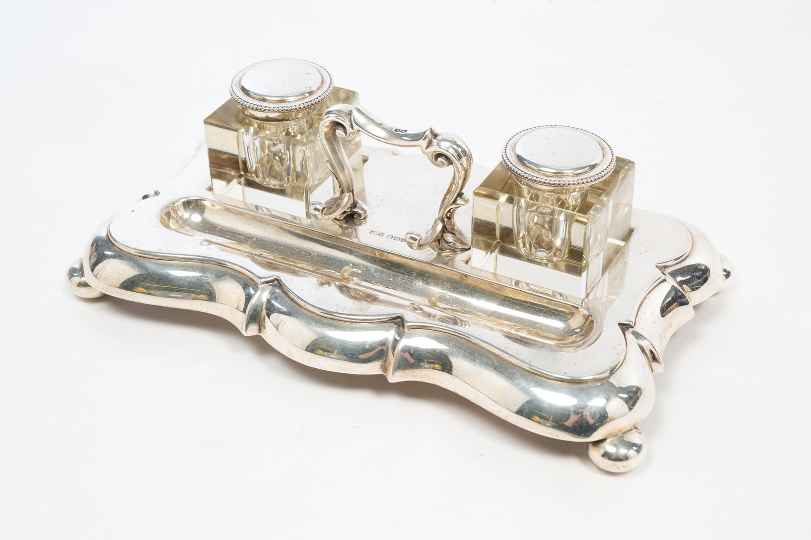 SHEFFIELD STERLING SILVER INK STAND.: SHEFFIELD STERLING SILVER INK STAND. English, Second quarter 20th Century. Handle with pen rack, shaped tray with two cut glass cube inkwells with sterling lids, pen well, and bun feet. Date mark for