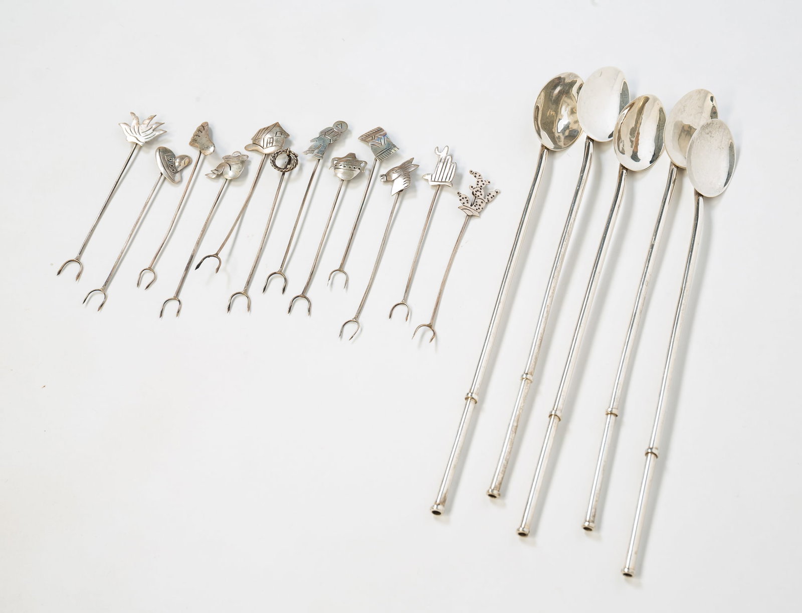 FIVE STERLING SILVER STIRRER STRAWS AND TWELVE COCKTAIL FORKS.: Mexican, 20th Century. Five stirrer straws marked on bottoms, 8.5"h., and twelve diminutive cocktail forks with southwestern-themed toppers, 3.5"h. Approximately 2.5 ozt.**Note: Bidders who are not
