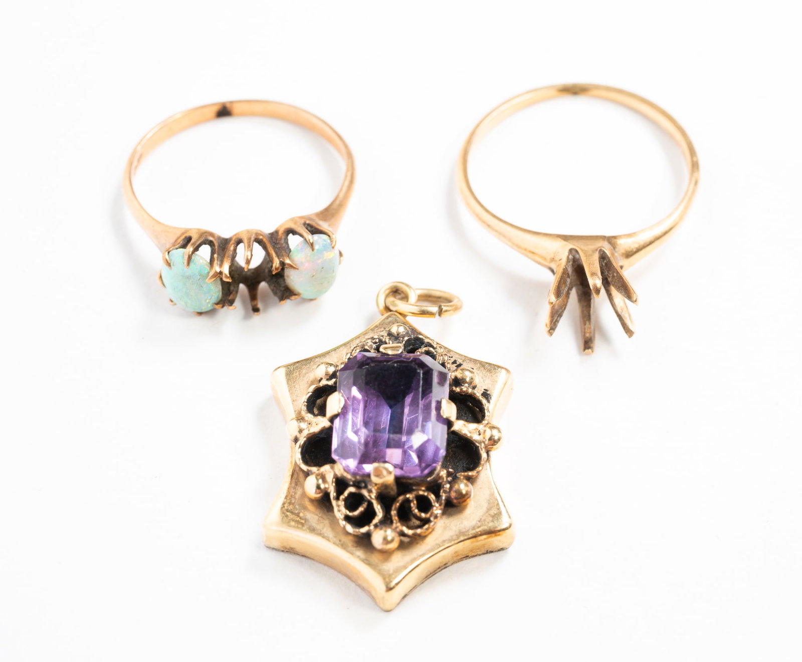 A 14K YELLOW GOLD PENDANT AND TWO RINGS.: 20th Century. A puffy-shaped pendant with scrollwork and set with an emerald-cut amethyst, 1.25"l. A solitaire prong set semi-mount, size 7.25, and a three-stone ring with two oval opals and one