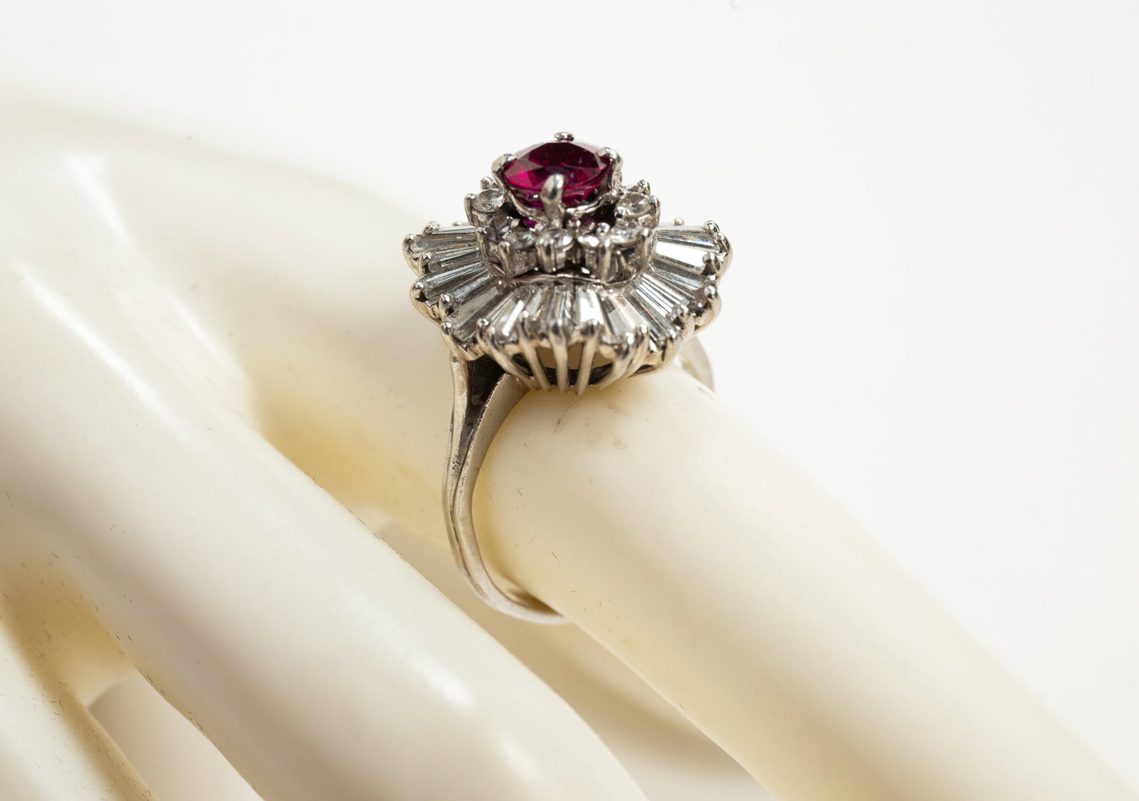 PLATINUM, DIAMOND AND RUBY COCKTAIL RING.: American, 20th century. Marked 'PLAT' ballerina style ring featuring center round faceted rubyencircled by twelve round diamonds, thirty-two tapered baguette diamonds radiate from the center. Estimate