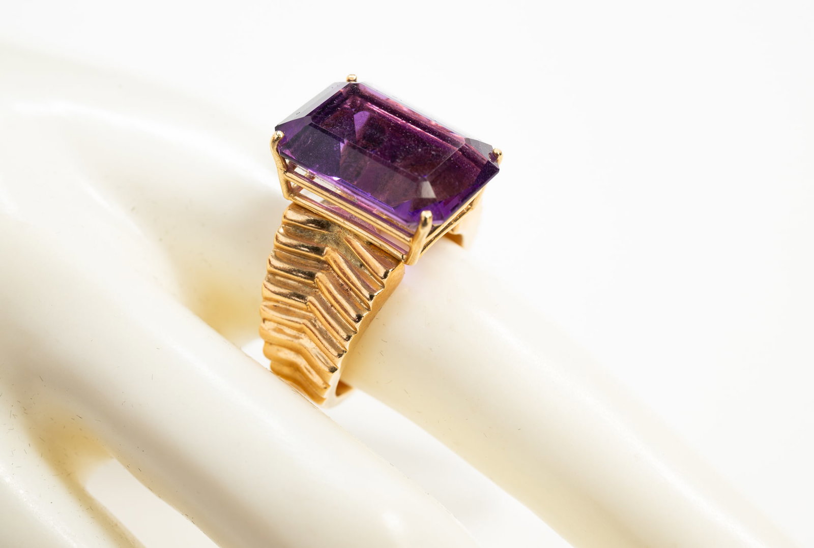 LADIES 14K YELLOW GOLD AND AMETHYST RING.: American, contemporary. Stamped '14K' ring featuring rectangular cut amethyst, approx. 14.62cts., prong mounted. Wide tapered band with ridged shoulders. Measures approx. 12.2mm at front, tapering to