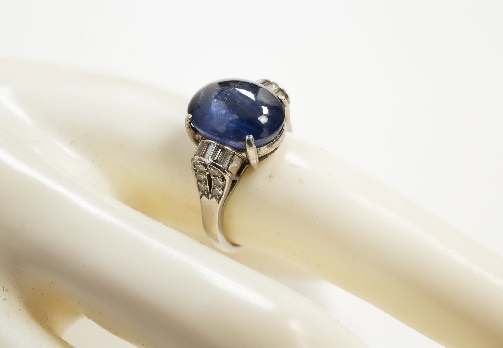 PLATINUM STAR SAPPHIRE AND DIAMOND RING.: American, late 20th century. Stamped '10% Irid.Plat' ring featuring oval cabochon star sapphire, bluish gray color. Sapphire measures approx. 12.6mm x 10.5mm x 7.7mm. Shoulders embellished with small