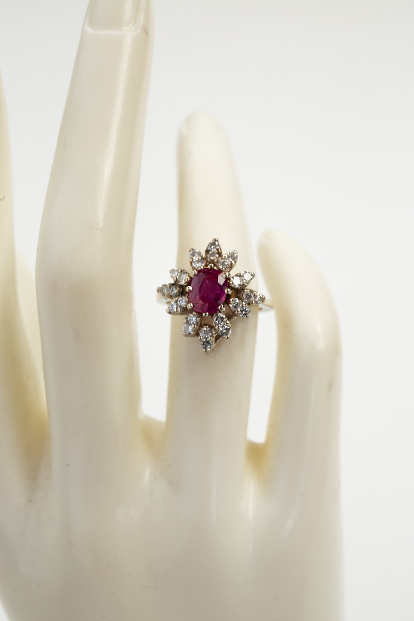 14K YELLOW GOLD RUBY AND DIAMOND COCKTAIL RING.: American, late 20th century. 14K yellow gold ring with center oval ruby, weighing approx. 1.11cts. Twelve pairs of round diamonds radiate out from the center ruby. Total diamond weight approx. 1.0ct,