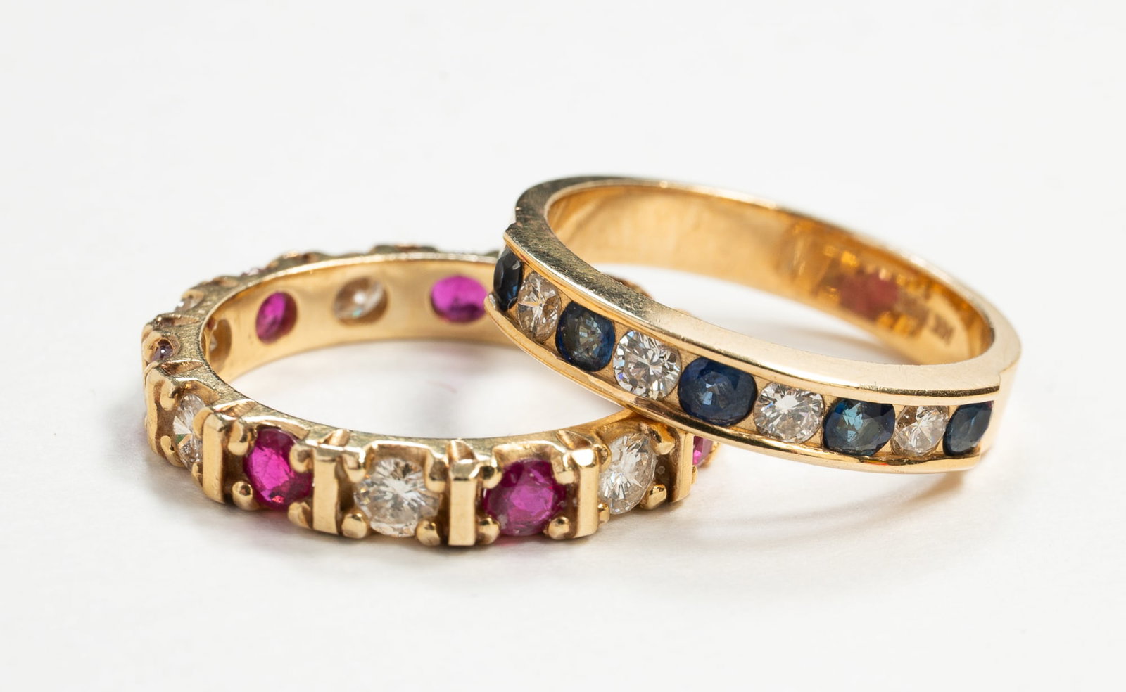 TWO GEM SET 14K YELLOW GOLD BANDS.: American, contemporary. One half hoop style ring marked '14K MCI', channel set with five round sapphires and four round brilliant diamonds. Total diamond weight approx. .22ct., ring size 6. One tested