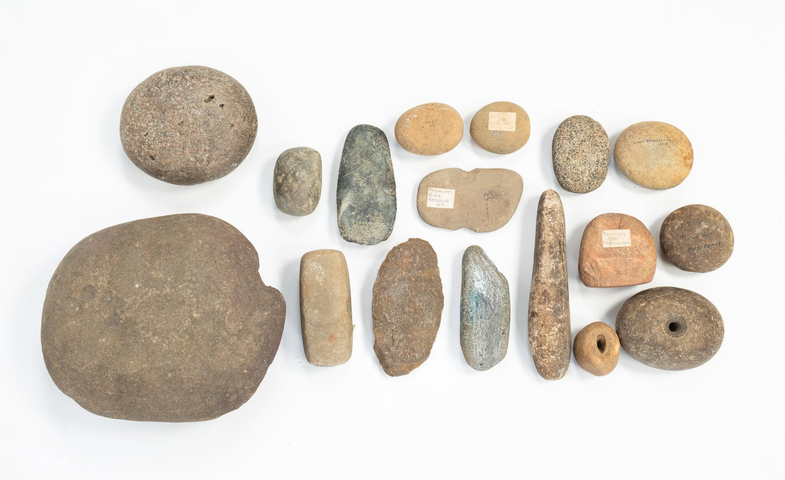 LARGE COLLECTION OF NATIVE AMERICAN STONE TOOLS.: LARGE COLLECTION OF NATIVE AMERICAN STONE TOOLS. Comprising approximately eighteen carved stone tools, including axe heads and round grind stones. Largest, 8.5"w. Provenance: From the Lifetime Collect