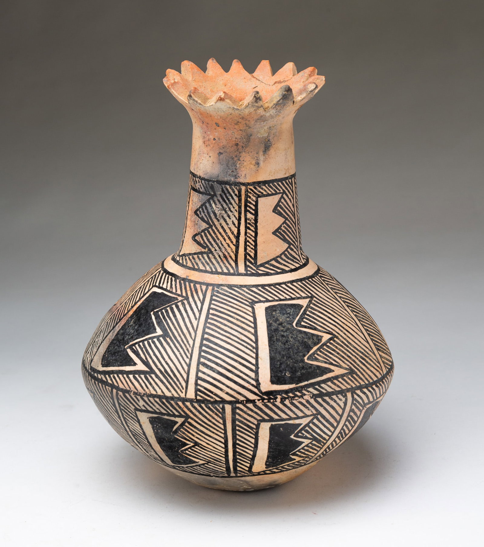 ACOMA PUEBLO PAINTED POTTERY VASE.: ACOMA PUEBLO PAINTED POTTERY VASE. New Mexico, Early 20th Century. Having a flared and serrated top rim, a long neck, and a bottle-form body, decorated with black lines and geometric shapes. The under