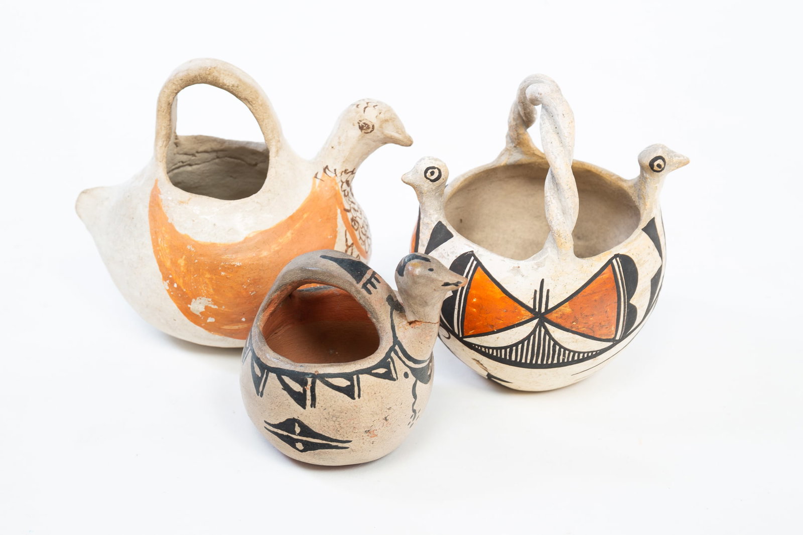 THREE NATIVE AMERICAN PUEBLO POTTERY BIRD POTS, INCL. ACOMA PUEBLO.: THREE NATIVE AMERICAN PUEBLO POTTERY BIRD POTS, INCL. ACOMA PUEBLO. New Mexico, Early-mid 20th Century. A pot with black and tan, painted decoration, two bird heads, twisted handle, and signed "Old Ac