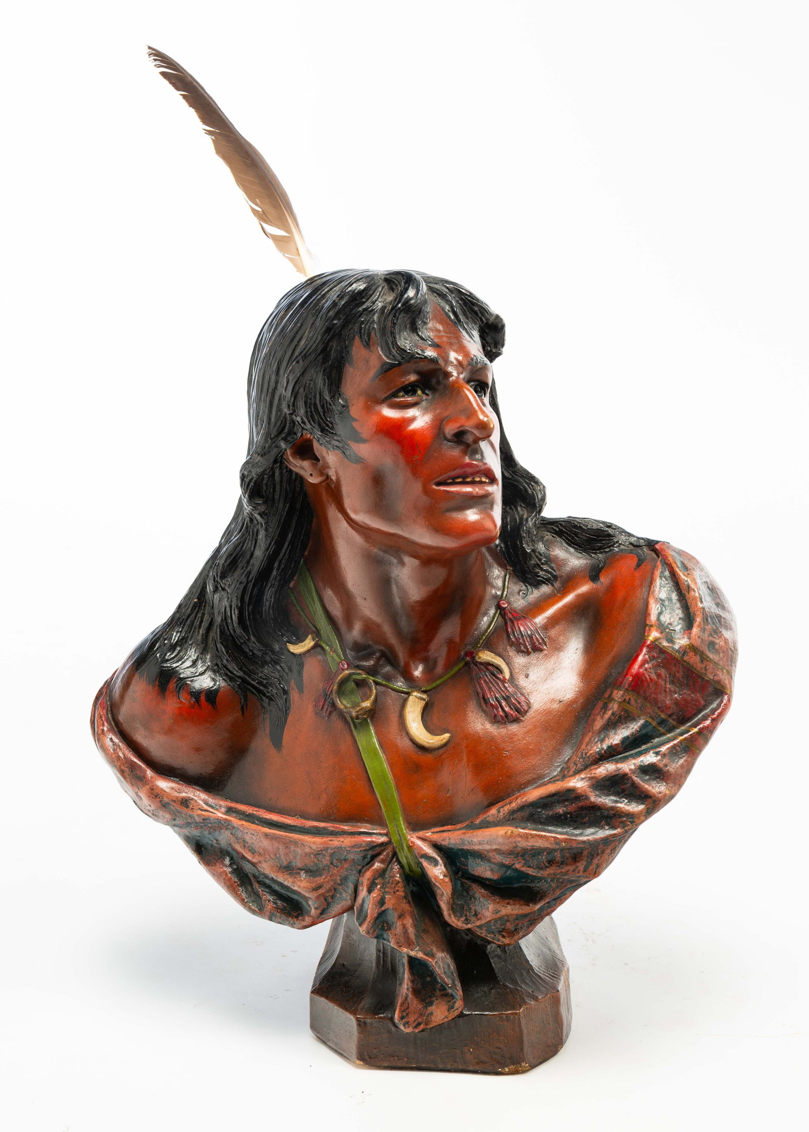 PLASTER BUST OF A NATIVE AMERICAN.: PLASTER BUST OF A NATIVE AMERICAN. American, Early 20th Century. Polychrome painted plaster bust of a Native American with long flowing hair with a real feather attached at the top of his head, a