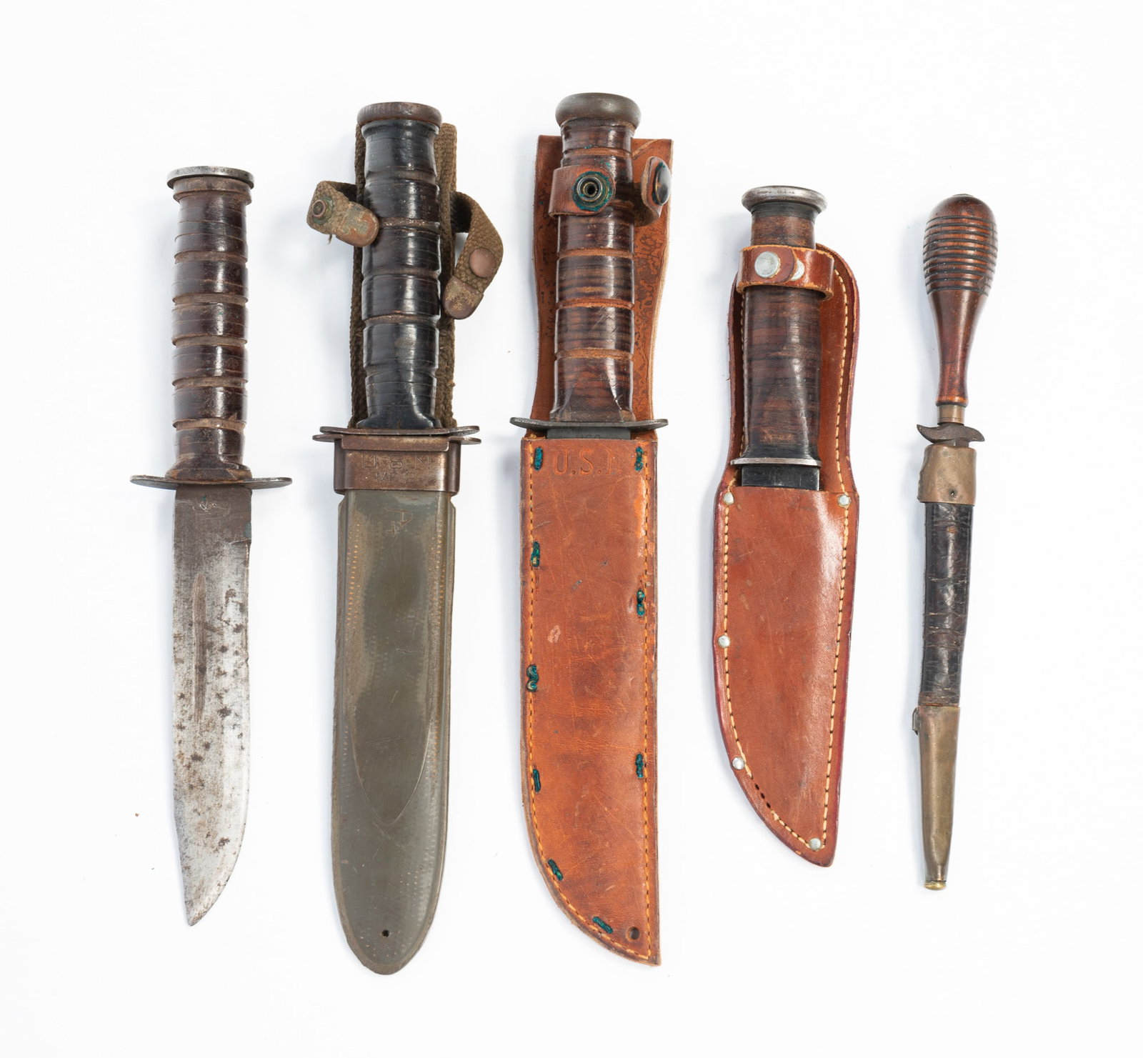FIVE MILITARY FIGHTING KNIVES.: FIVE MILITARY FIGHTING KNIVES. American, 19th-20th Century. A Civil War-era Naval dirk with turned wood knob handle and leather sheath with brass trim. Overall, 10.75"l. Two Ka-Bar (Olean, New York) B