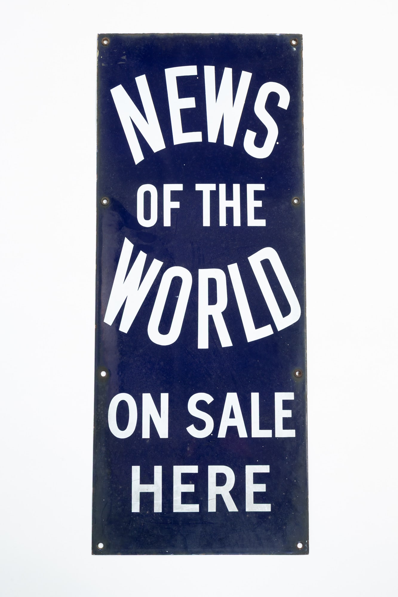 ENGLISH "NEWS OF THE WORLD ON SALE HERE" ENAMELED SIGN.: ENGLISH "NEWS OF THE WORLD ON SALE HERE" ENAMELED SIGN. 20th Century. Iron with cobalt blue background and white block lettering. 30"h. 12"w. Provenance: From the late George Shahady (Bridgeport,