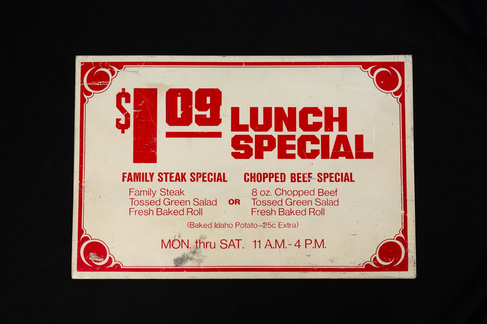 "LUNCH SPECIAL" ENAMELED TIN RESTAURANT SIGN.: "LUNCH SPECIAL" ENAMELED TIN RESTAURANT SIGN. American, Mid-20th Century. Red lettering and decoration on a tan ground, reading "$1.09 Lunch Special" with choices underneath. 16"h. 24"w. Provenance: