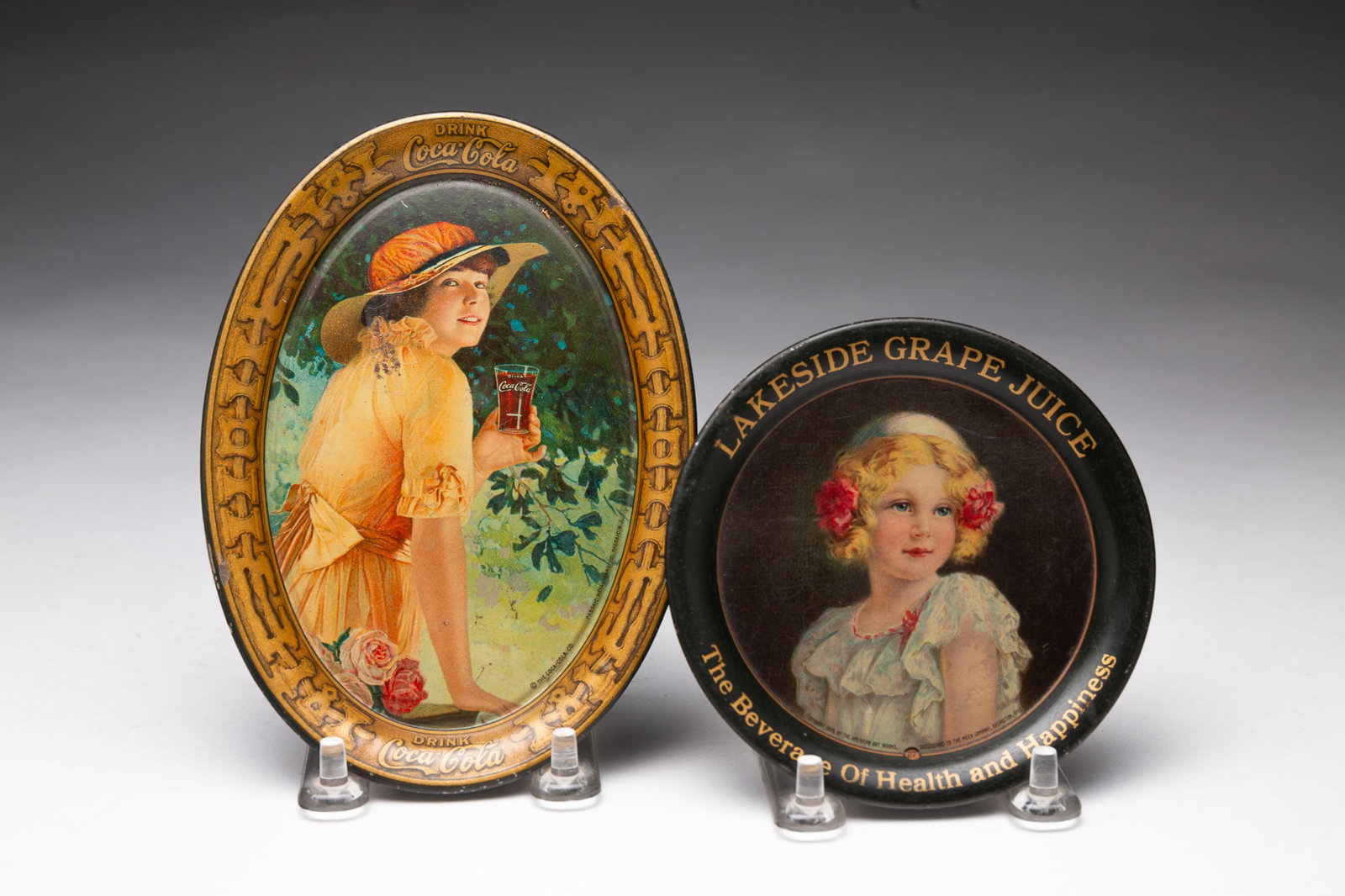 TWO AMERICAN ADVERTISING TIP TRAYS.: TWO AMERICAN ADVERTISING TIP TRAYS. First quarter 20th Century. Round "Lakeside Grape Juice" with young girl at center by American Art Works, Coshocton, Ohio Copyright 1909, 4.25"d. and an oval