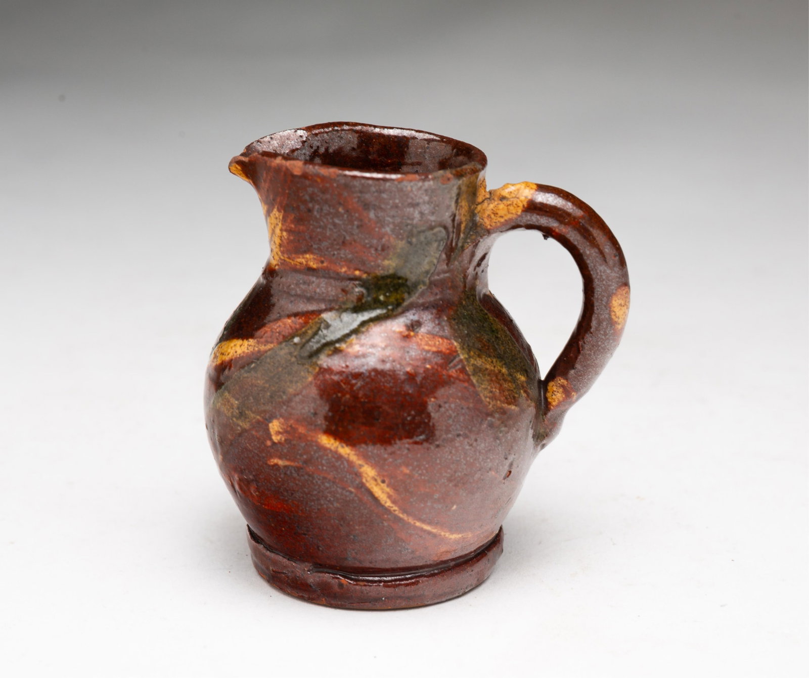 SCARCE MINIATURE POLYCHROME SLIP DECORATED REDWARE PITCHER ATTRIBUTED TO BERKS COUNTY, PENNSYLVANIA. (1 of 6)