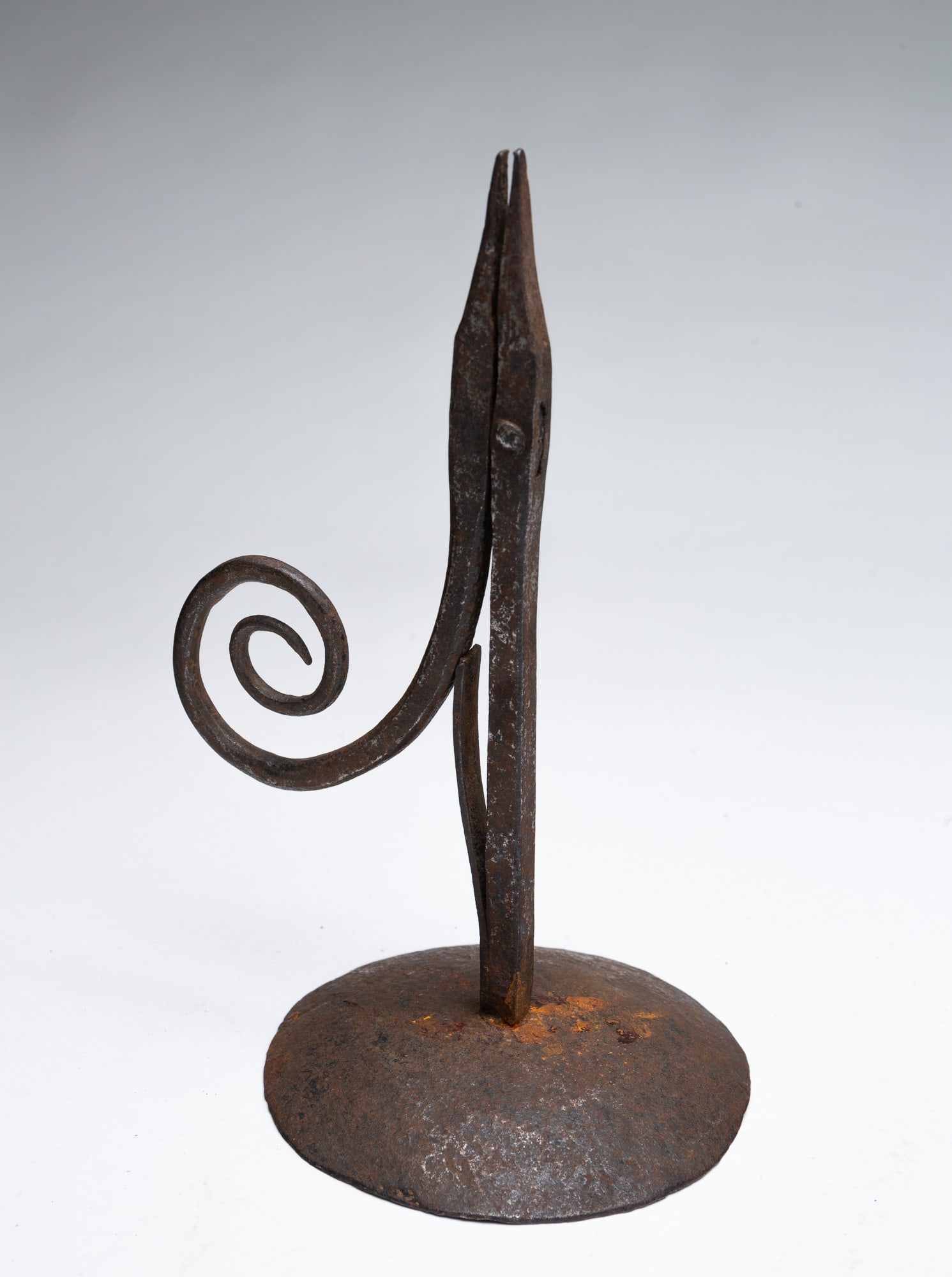 WROUGHT IRON TABLE-TOP RUSH LIGHT.: WROUGHT IRON TABLE-TOP RUSH LIGHT. American, 19th Century. Wrought iron shaft with scrolled arm and circular base. 8.25"h. The Lifetime Provenance: Collection of the late Nancy Goff (Alliance, Ohio);