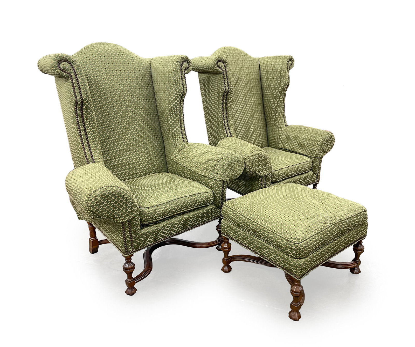 PAIR OF LEE JOFA WILLIAM AND MARY STYLE WINGBACK ARMCHAIRS AND OTTOMAN.: PAIR OF LEE JOFA WILLIAM AND MARY STYLE WINGBACK ARMCHAIRS AND OTTOMAN. Late 20th-early 21st Century. Large-scale green patterned upholstery, paneled legs, curved "X" stretchers with pinecone
