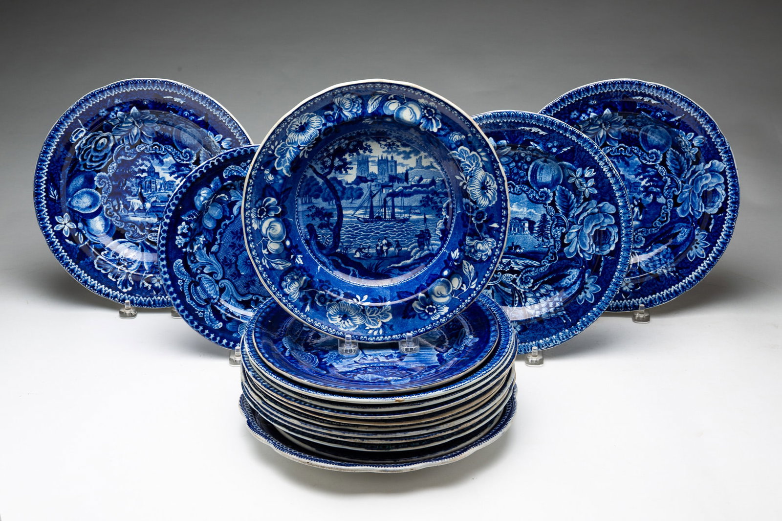 GROUP OF STAFFORDSHIRE BLUE TRANSFERWARE PLATES AND BOWLS.: GROUP OF STAFFORDSHIRE BLUE TRANSFERWARE PLATES AND BOWLS. English, 19th Century. Including plates featuring scenes from Blenheim, Perthshire, Fonthill Abbey, Pains Hill, Surrey, Llanarth Court,