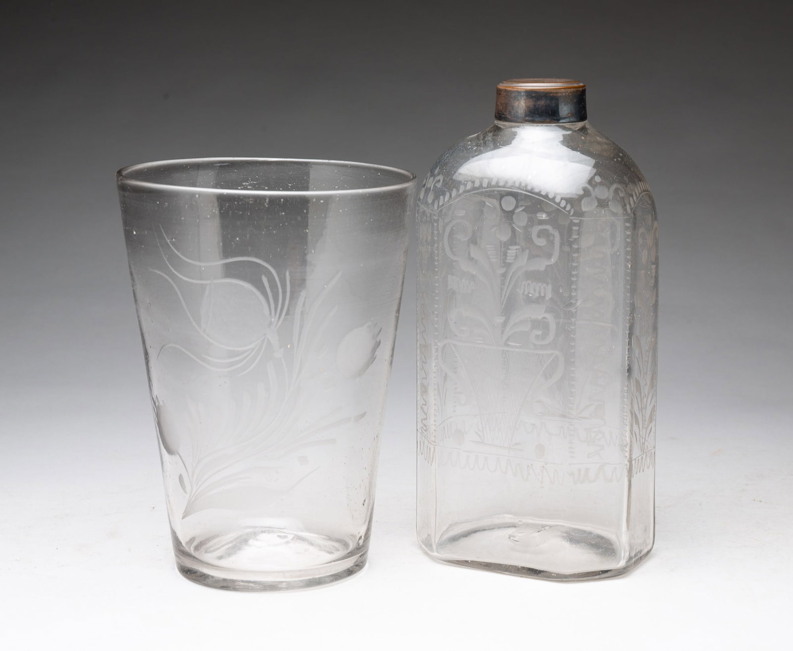 BLOWN FLINT GLASS FLIP AND DECANTER WITH ETCHED DETAILING.: BLOWN FLINT GLASS FLIP AND DECANTER WITH ETCHED DETAILING. American, 19th Century. A blown glass flip with broken pontil and etched poppies, 8.25"h., and a blown decanter with squared form, short