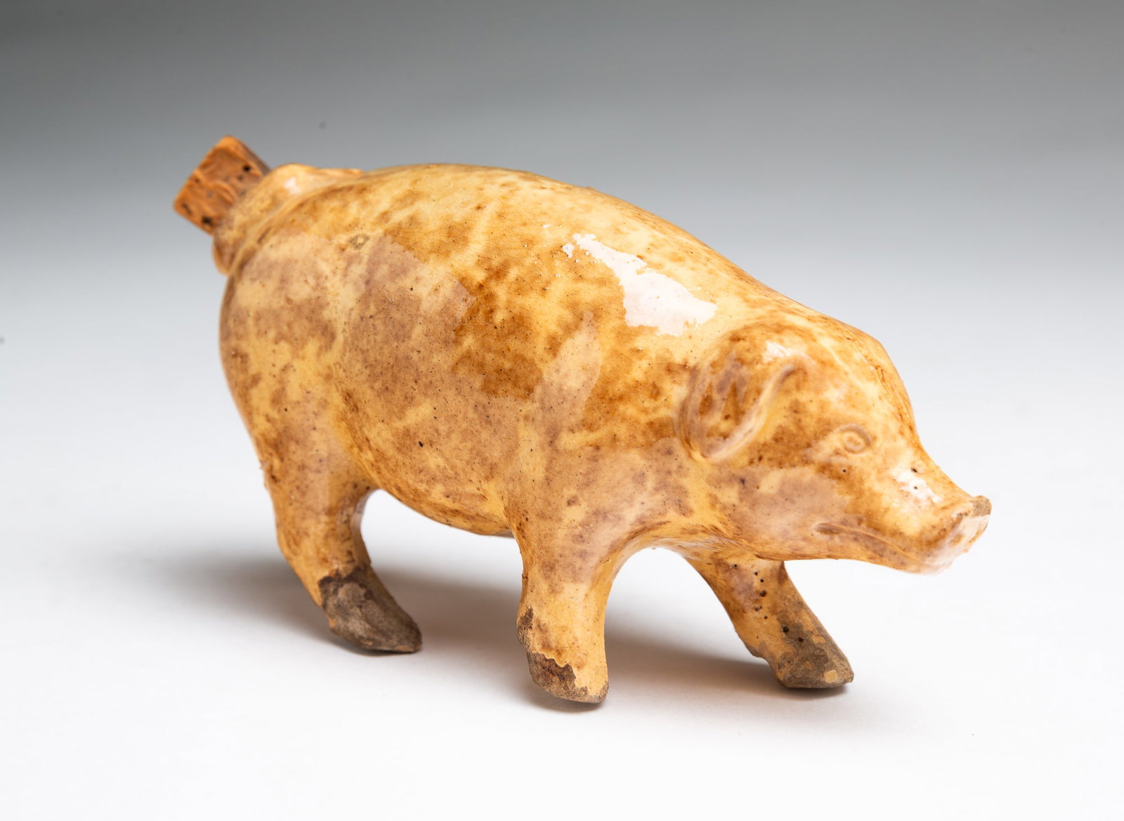 PIG-SHAPED FLASK WITH ROCKINGHAM GLAZE.: PIG-SHAPED FLASK WITH ROCKINGHAM GLAZE. American, 19th Century. Well molded with mottled brown glaze. 2.5"h. Provenance: The Lifetime Collection of Martha Magsig Lynch (Centerville, Ohio).