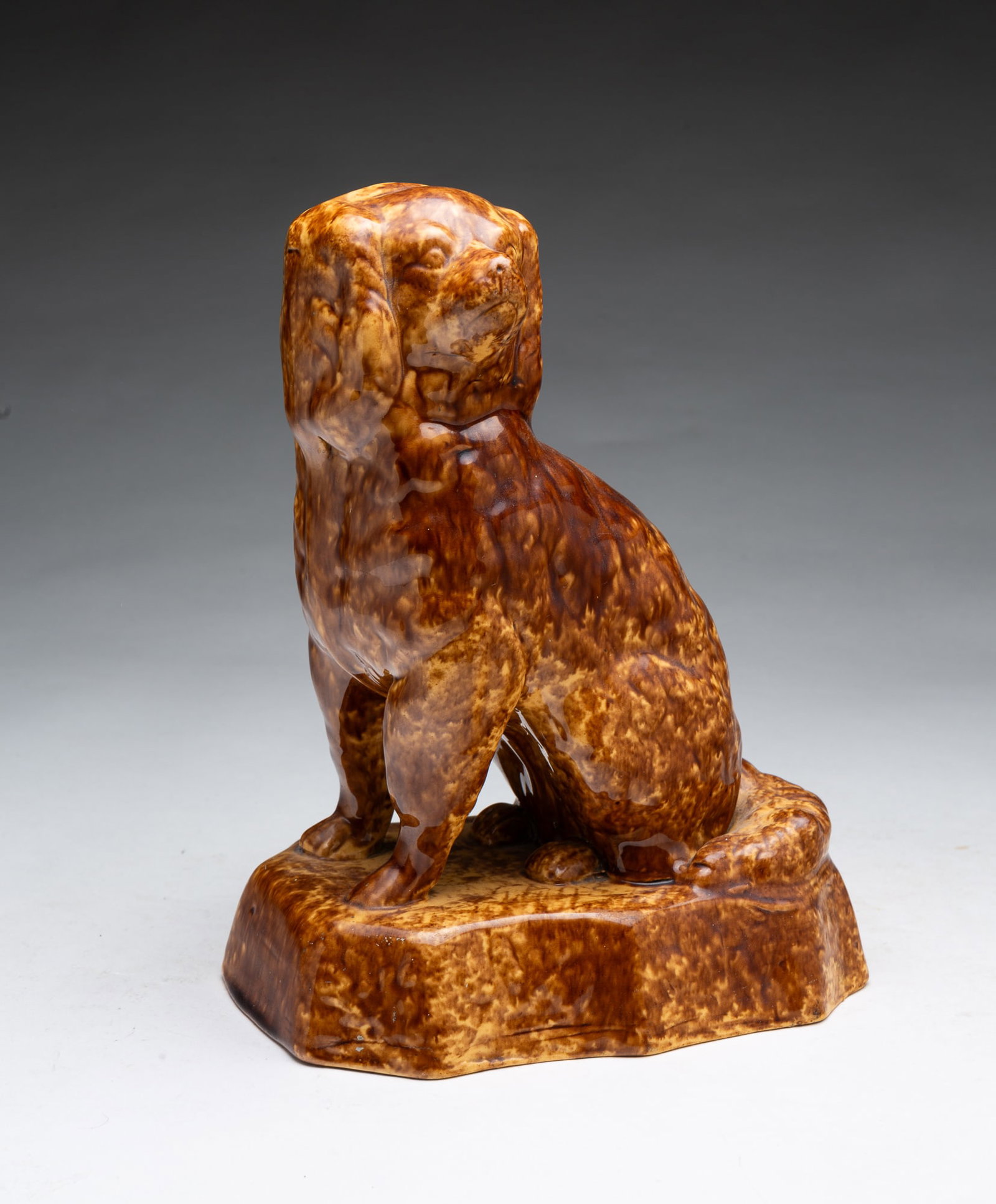 YELLOWWARE SEATED SPANIEL WITH ROCKINGHAM GLAZE.: YELLOWWARE SEATED SPANIEL WITH ROCKINGHAM GLAZE. American, 19th Century. Nicely molded with free-standing front legs and on a plinth with rounded corners. 10"h. Provenance: From the Lifetime