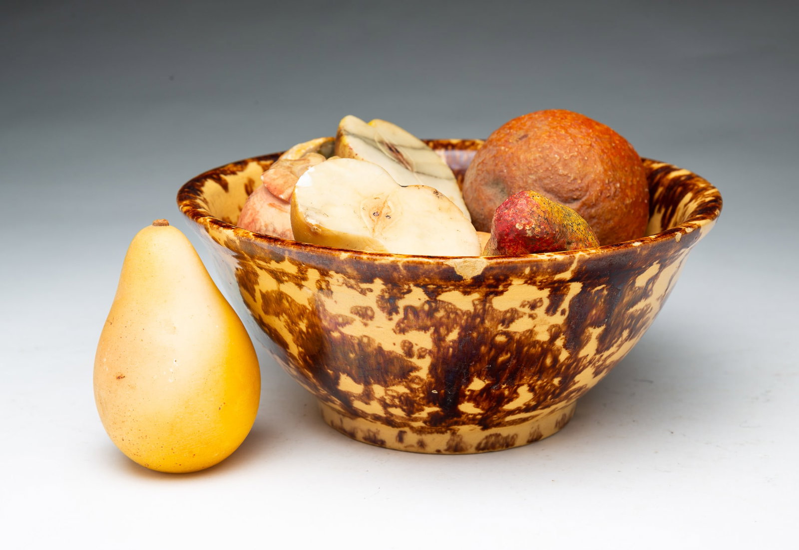 ROCKINGHAM BOWL WITH NINE PIECES OF STONE FRUIT.: ROCKINGHAM BOWL WITH NINE PIECES OF STONE FRUIT. English and European, 19th and 20th Centuries. Yellowware bowl with brown mottled glaze. Fruit included two pears, peach, orange, strawberry,