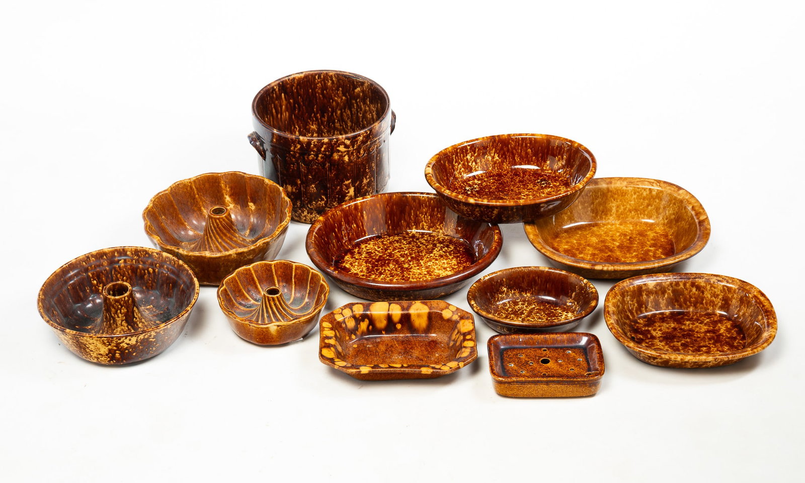ROCKINGHAM GLAZE POTTERY FOOD MOLDS AND DISHES.: ROCKINGHAM GLAZE POTTERY FOOD MOLDS AND DISHES. American, Mid to late 19th Century. Eleven glazed items. Including a tall cylindrical jar with patterned sides and applied handles, oval serving dishes,